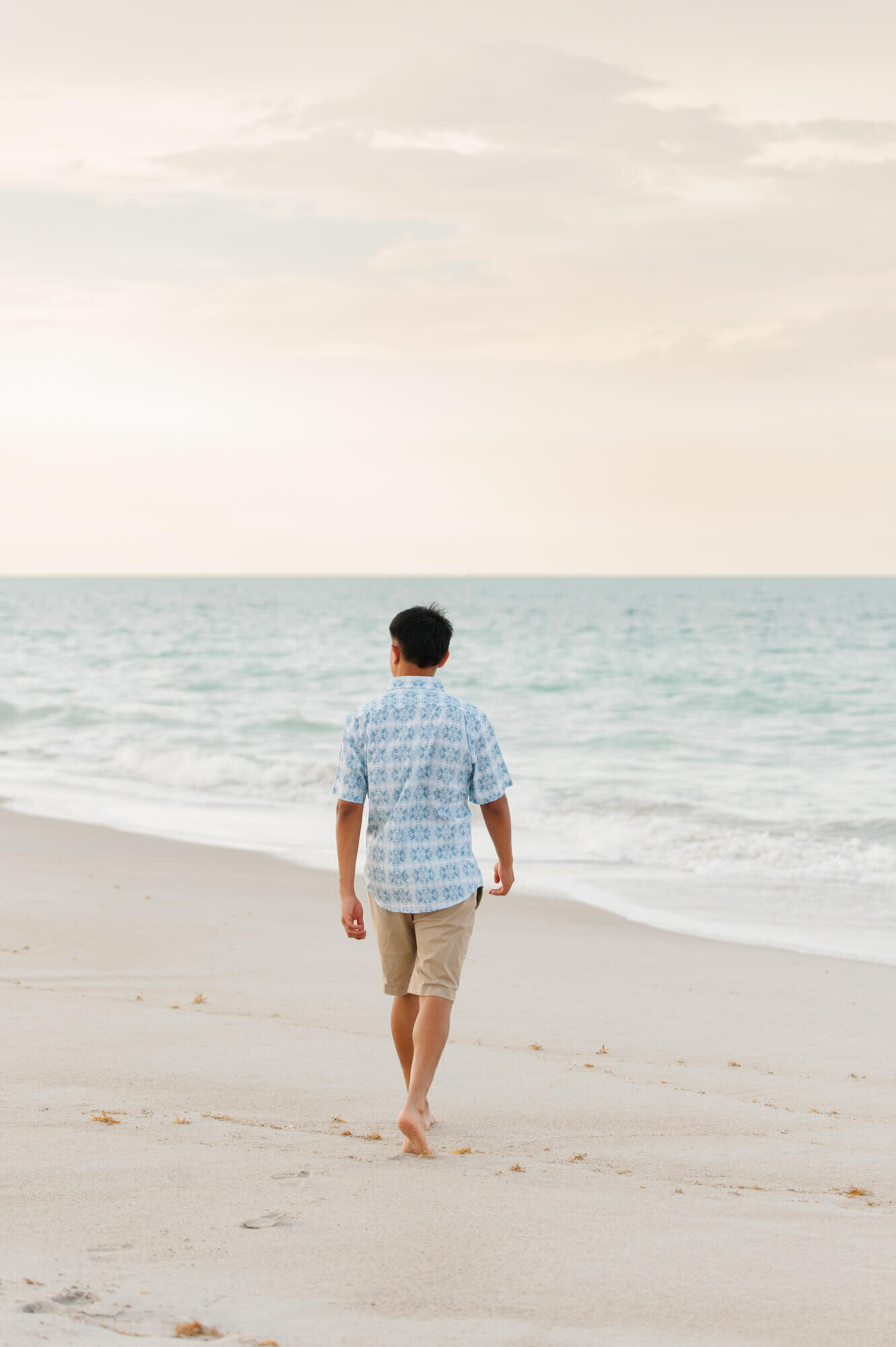 Orlando senior boy walking toward the ocean during his senior portrait session