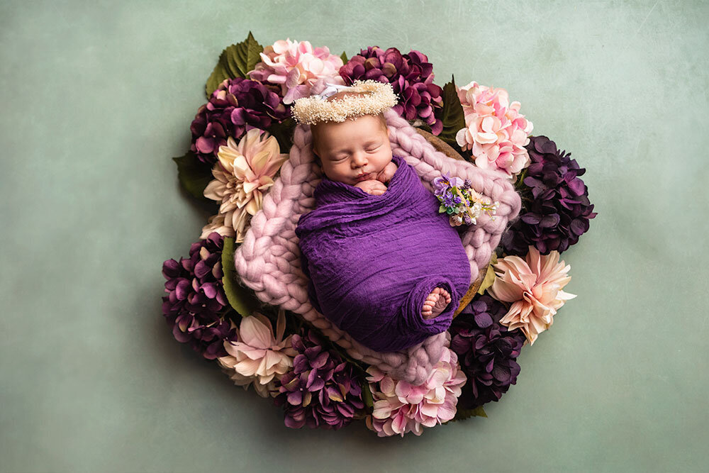 baby-girl-floral-purple-pink-white-flowers-in-basket-baby-breath-halo-headband-flower-newborn-green-background-lavender-mint-colors-luxury-premier-photographer-colorado
