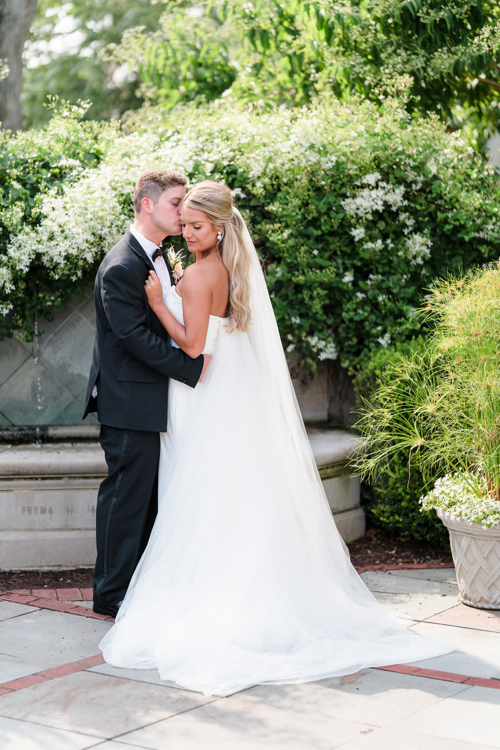 Groom kisses his wife's cheek in the gardens at the Franklin Park Conservatory