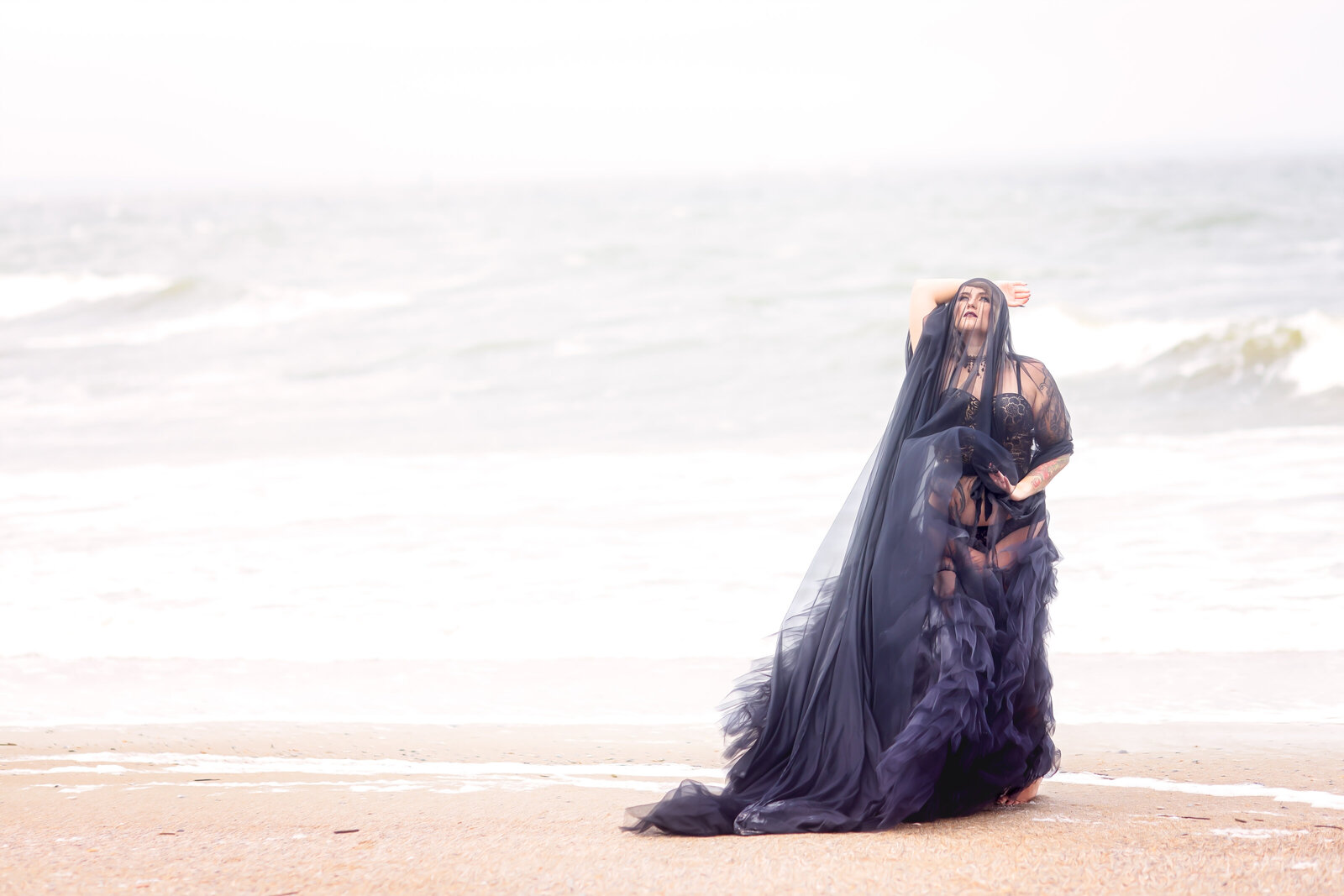 Woman in black gown on beach woth black veil over face
