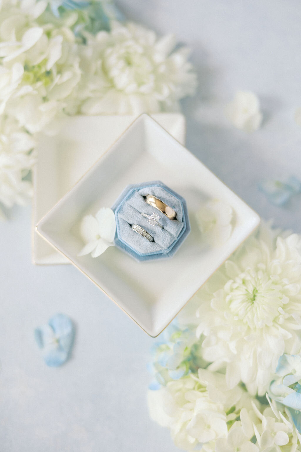 Blue background flat lay for wedding rings with white flowers