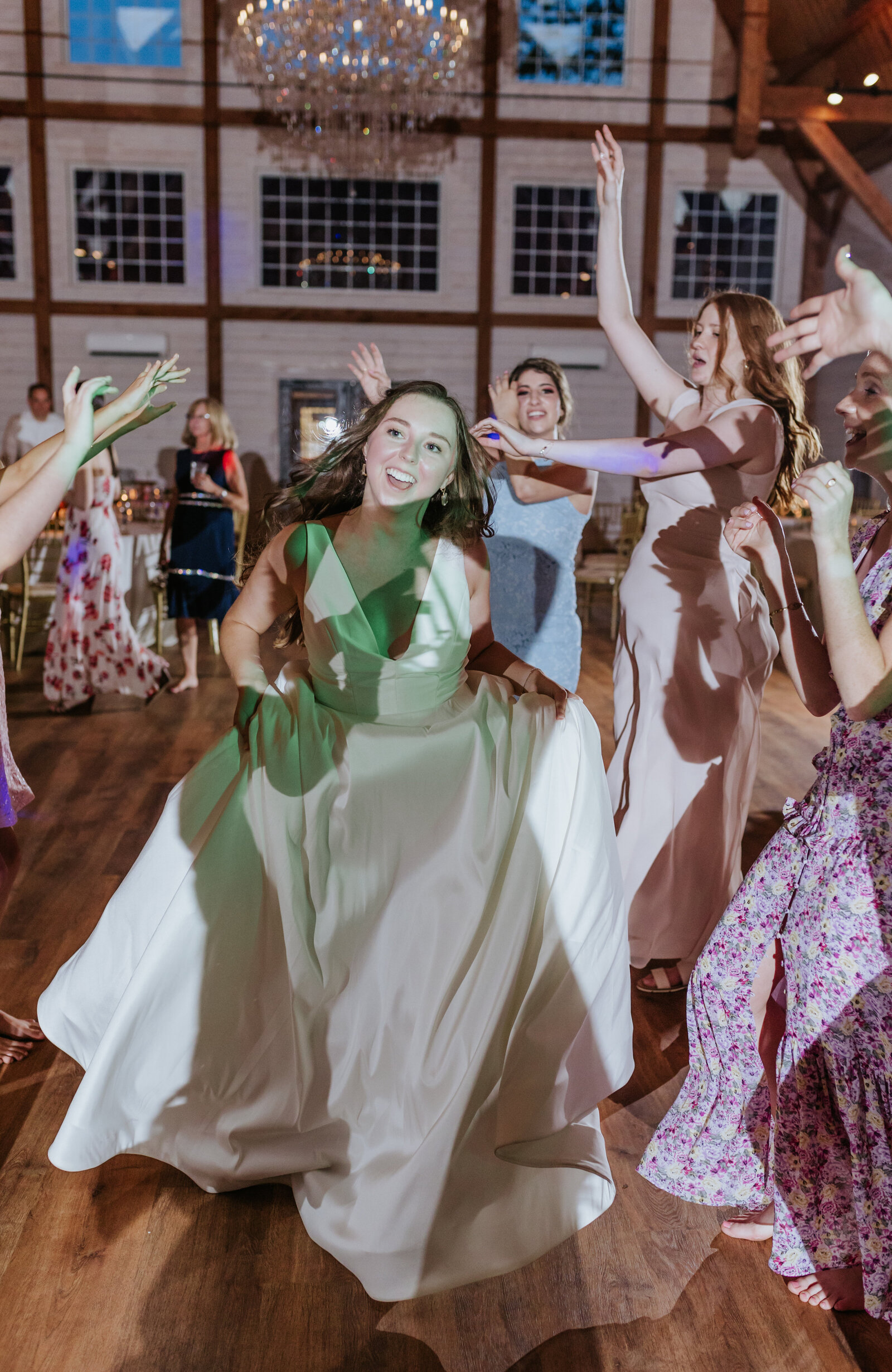 A bride dances through a line of guests at a barn wedding reception