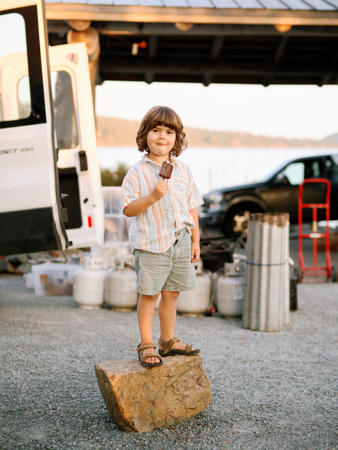 Young wedding guest stands on a rock eating an ice cream