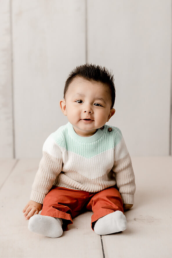 Baby with spiky hair smiles for his One Year Old photo session.