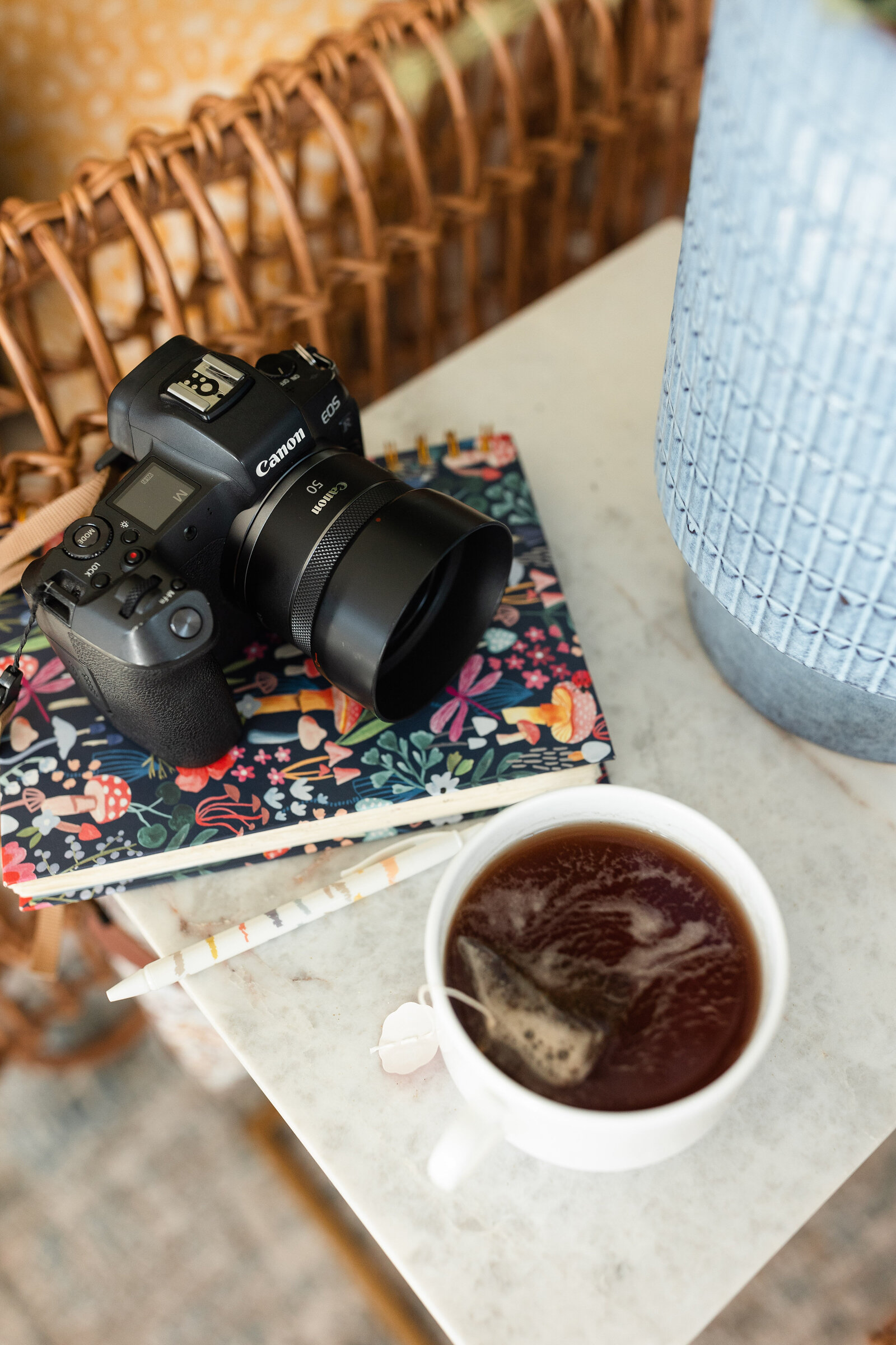mug of hot tea, camera, and journal styled on a side table