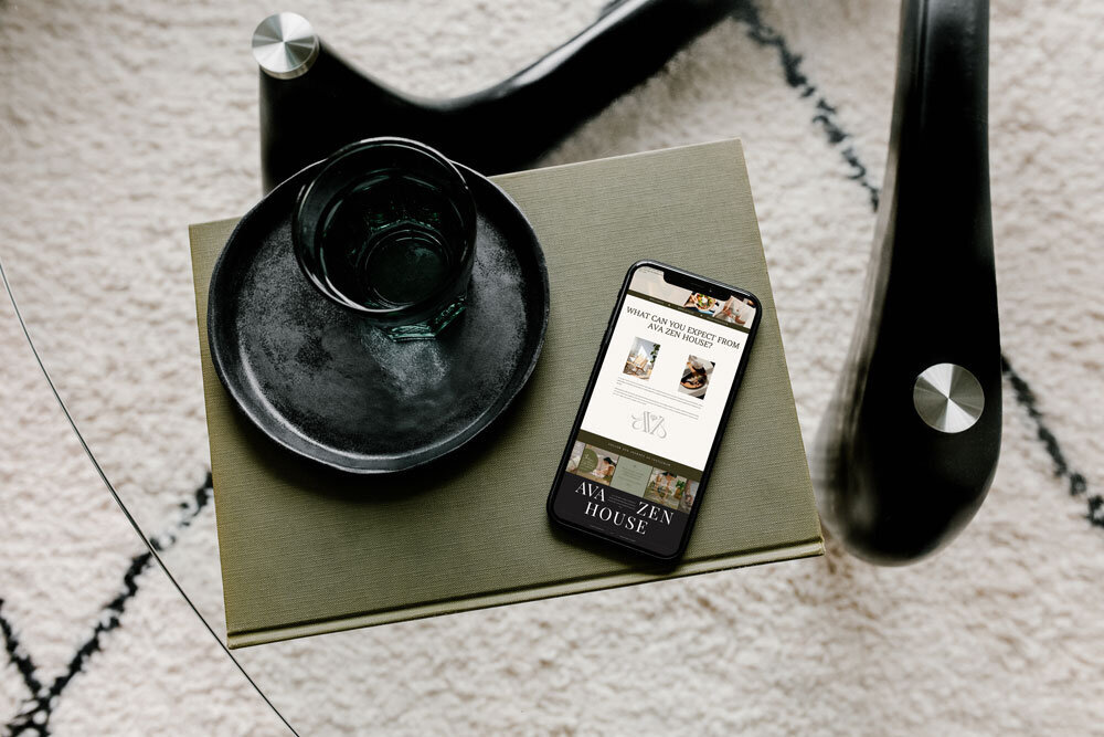 iPhone displaying Ava Zen wellness website on a rustic wooden table, showcasing holistic branding for wellness entrepreneurs.