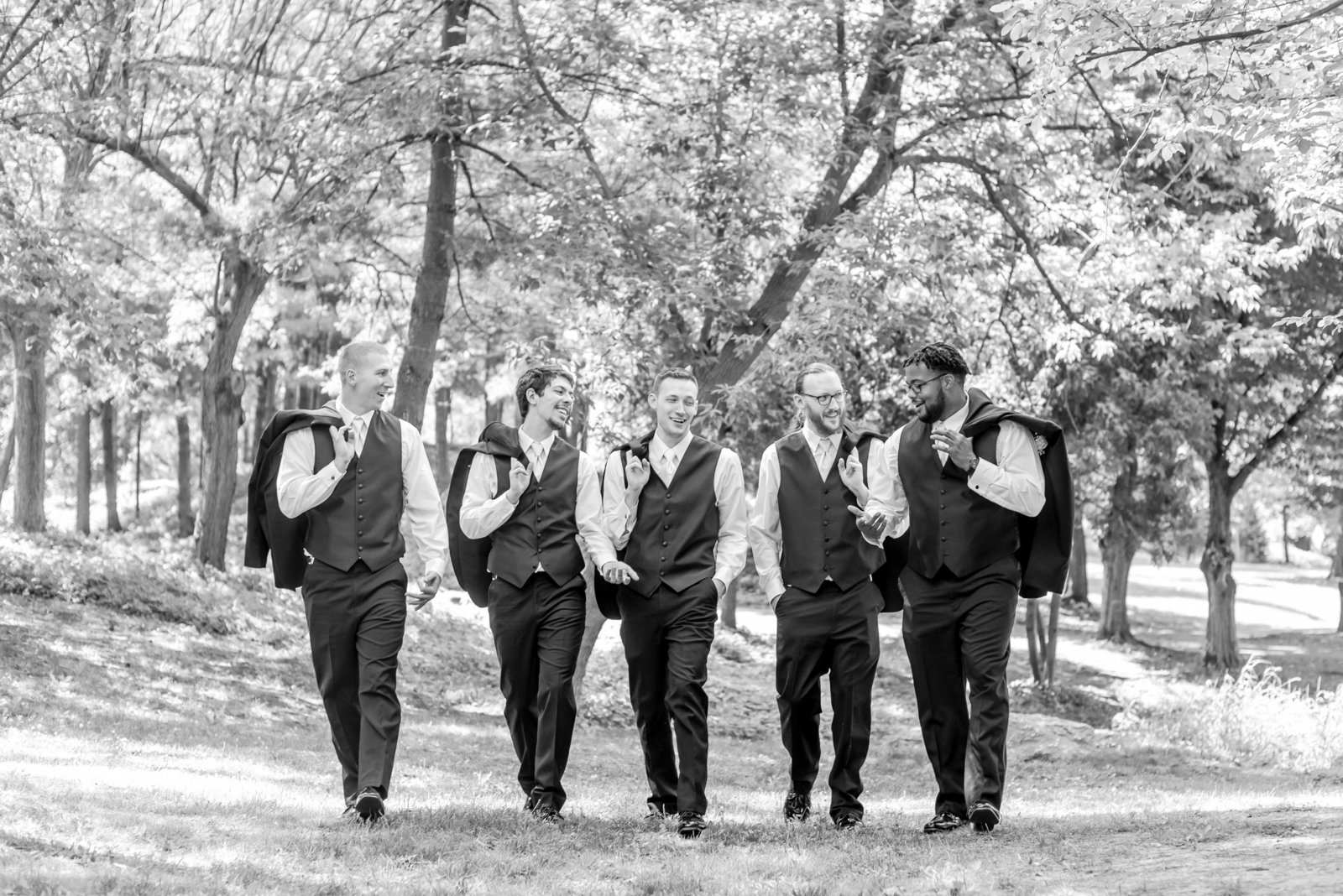 Groomsmen walk together with jackets thrown over their shoulders