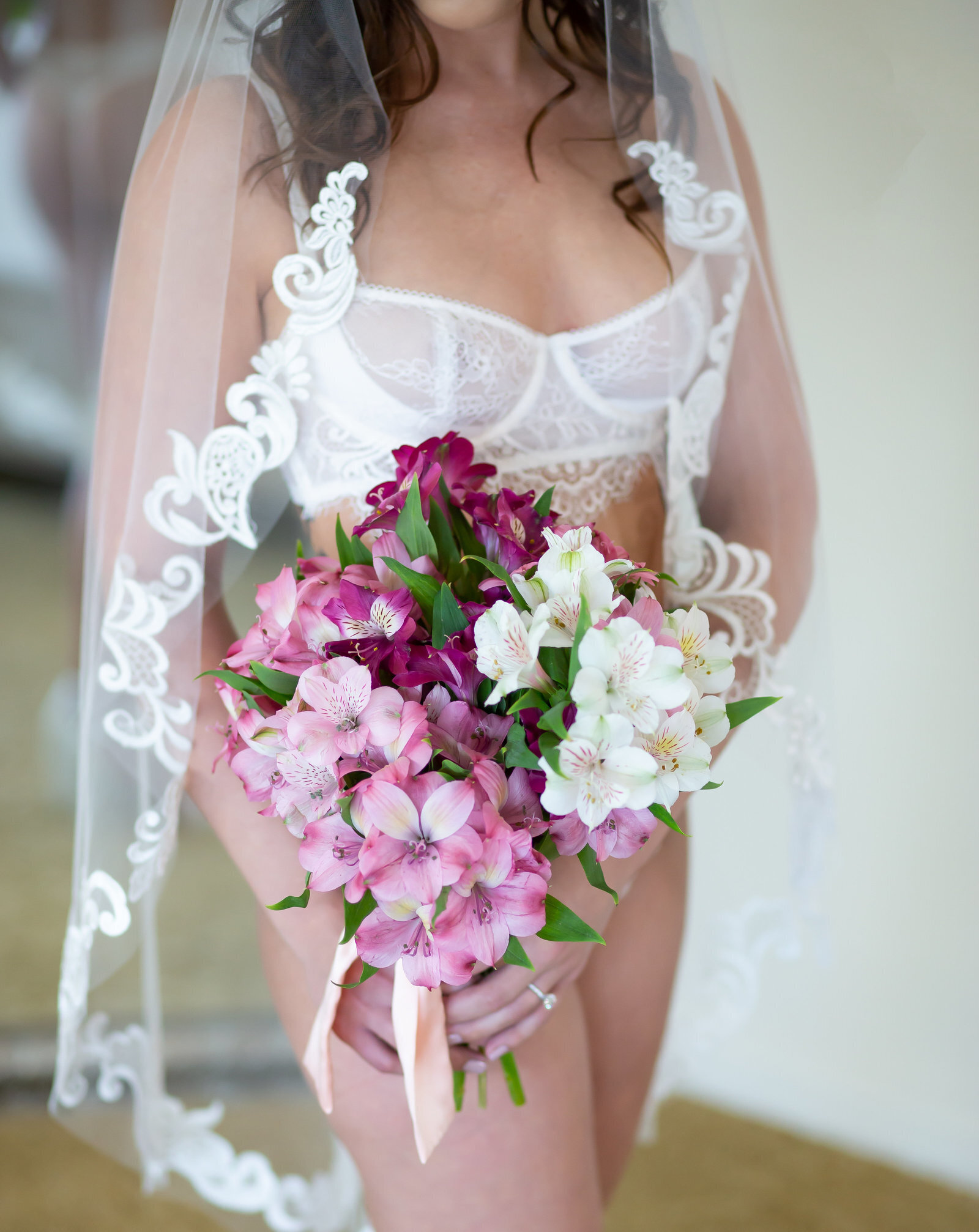 Bride holding purple florals and lace veil, boudoir shoot