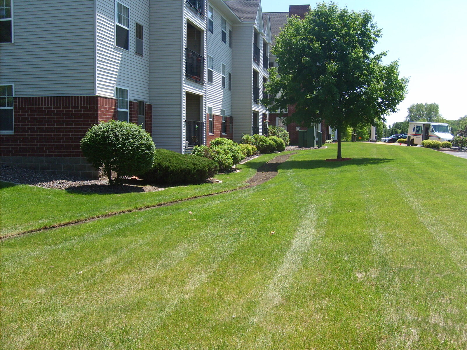 Commercial lawn care in front of white apartment buildings