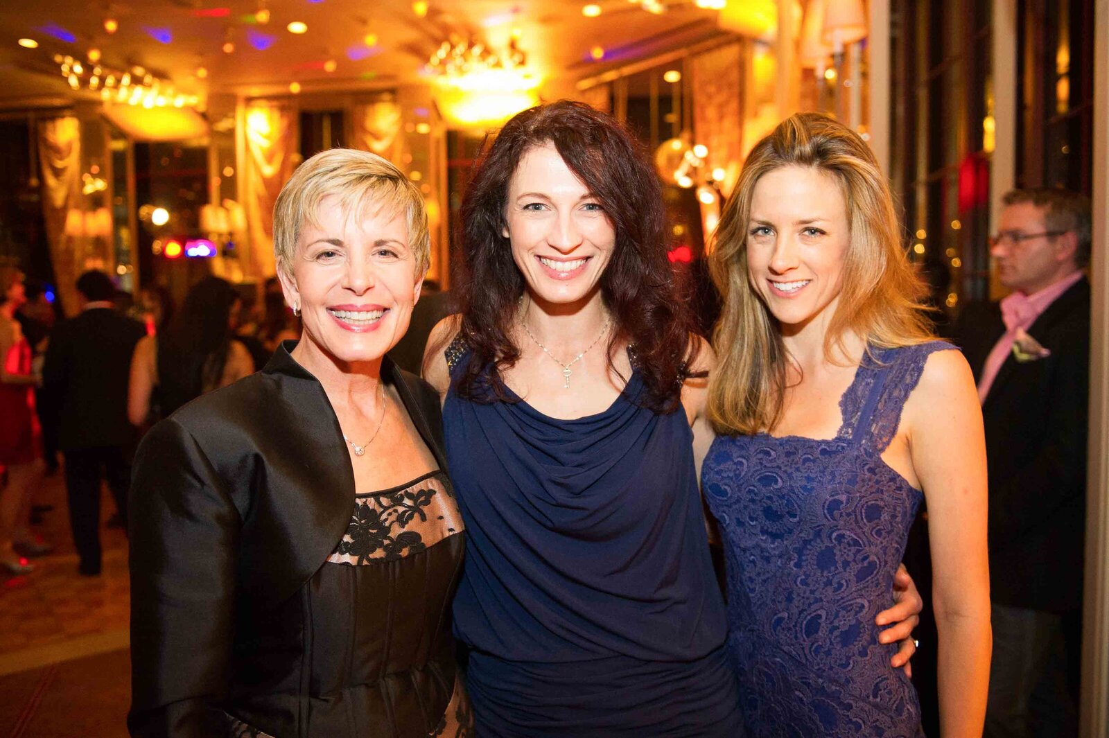 Holiday party, three women smiling for the camera.-