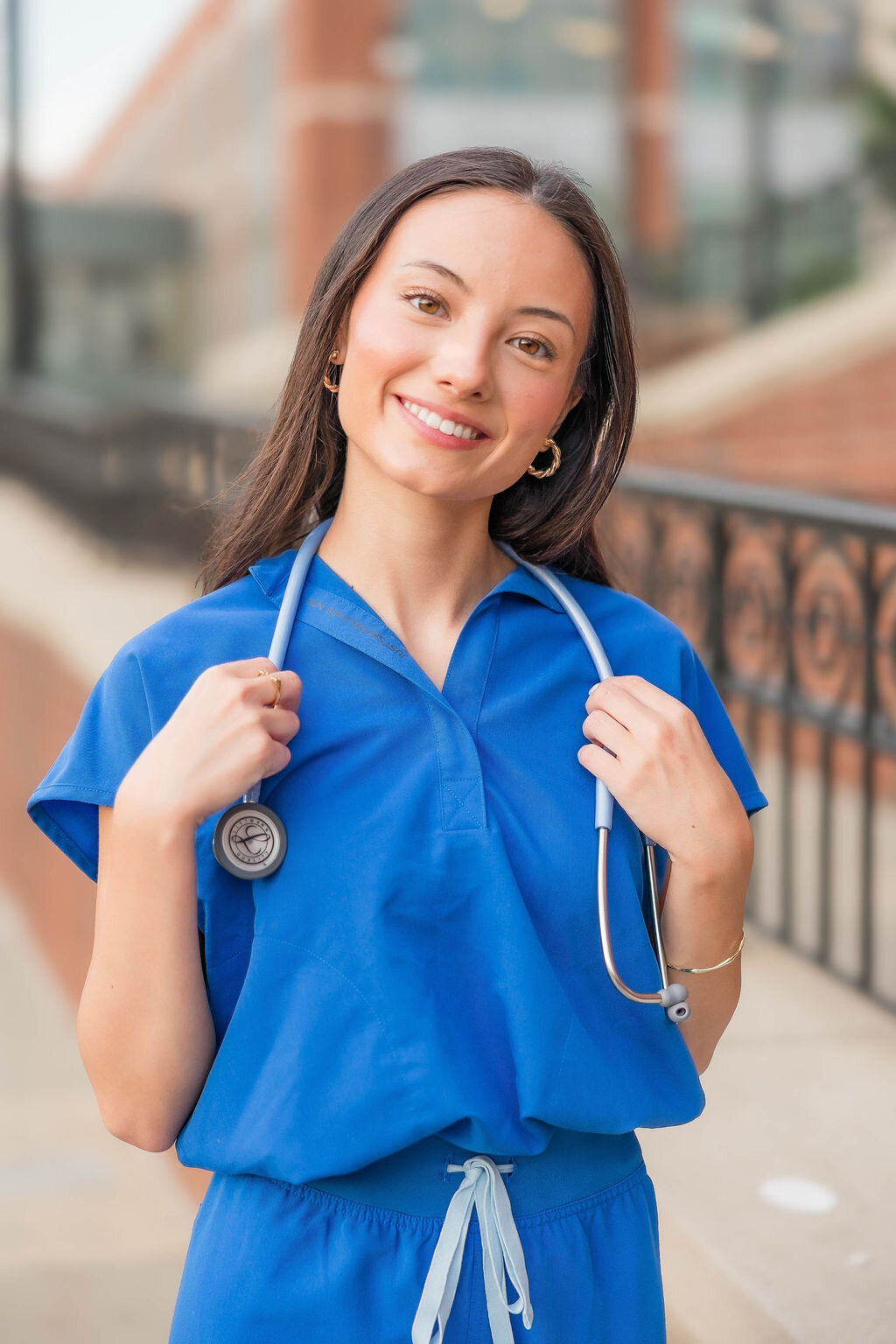 Girl in nursing attire smiling at camera during a college graduation milestone photo session in Charlotte NC