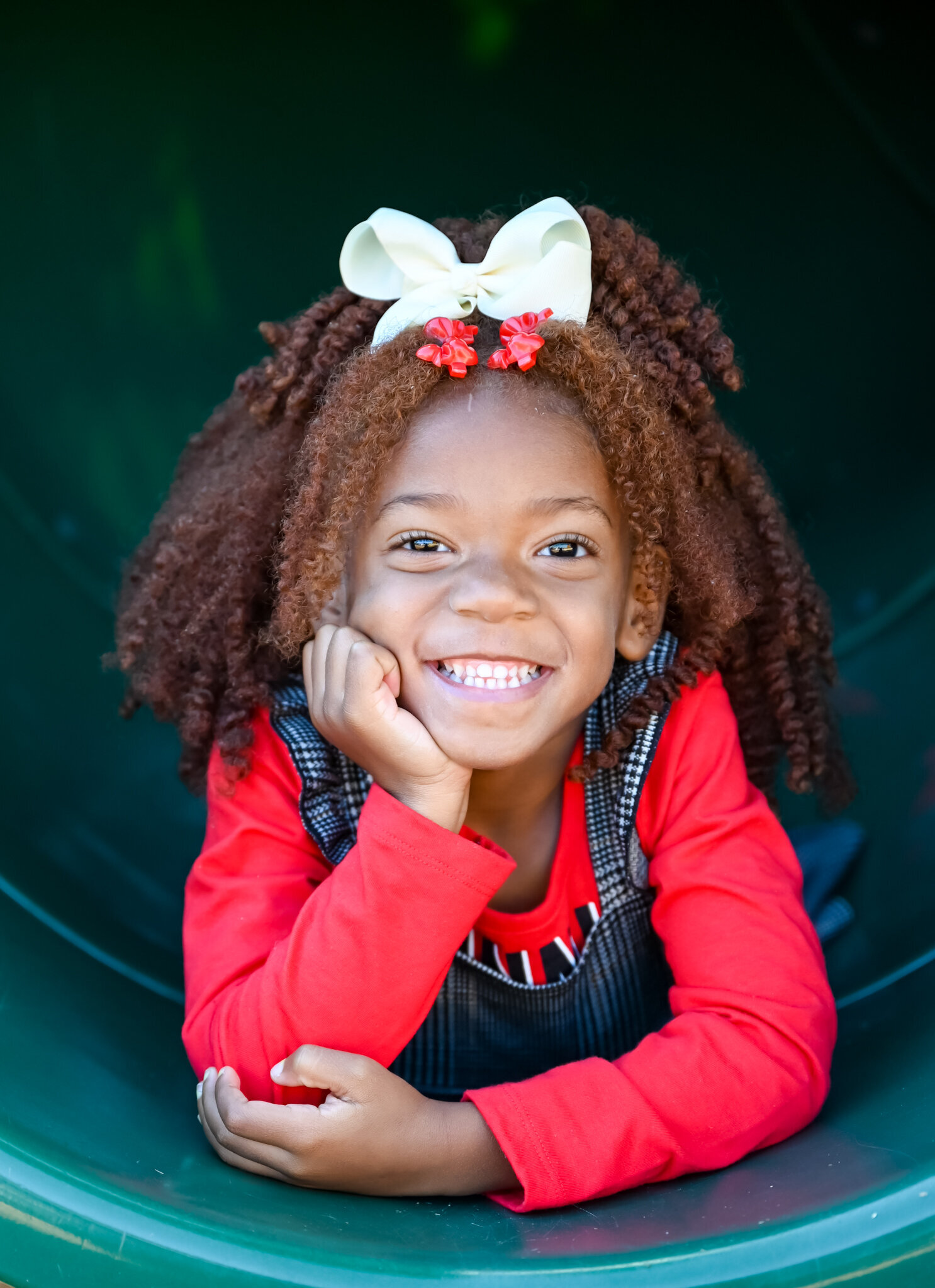 young girl posing for a photo inside of a slide smiling at the camera photographed by Millz Photography in Greenville, SC