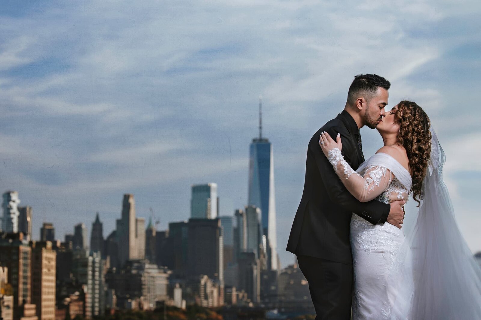 Luxury wedding portrait by Logrono & Co. featuring a bride and groom kissing with the New York City skyline and One World Trade Center in the background, captured in cinematic style.