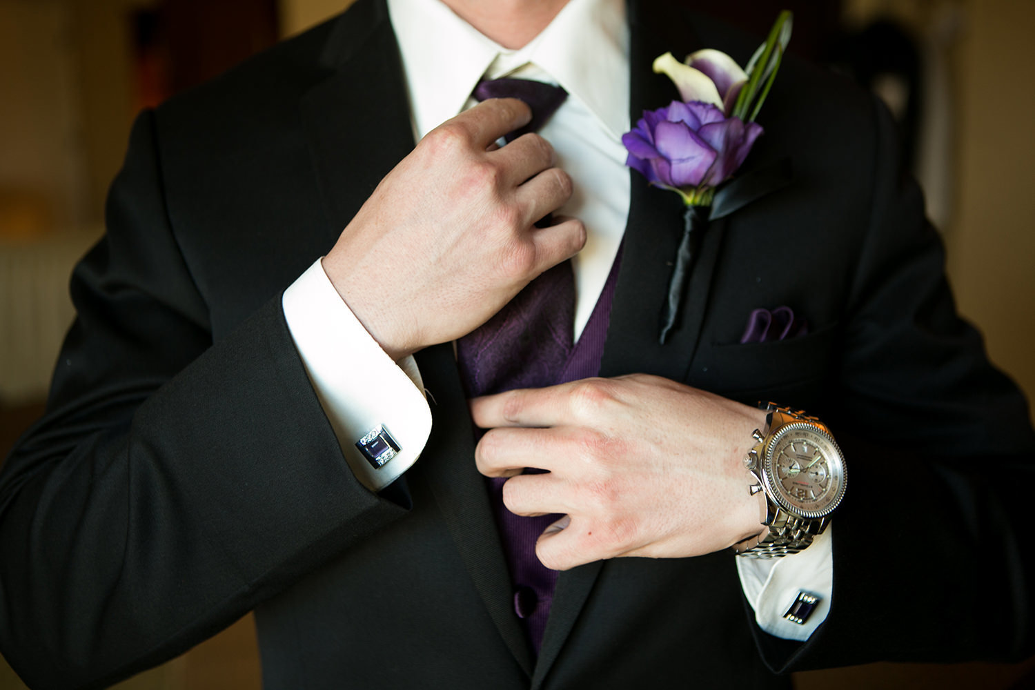 Detail photo of groom adjusting his tie before the wedding.