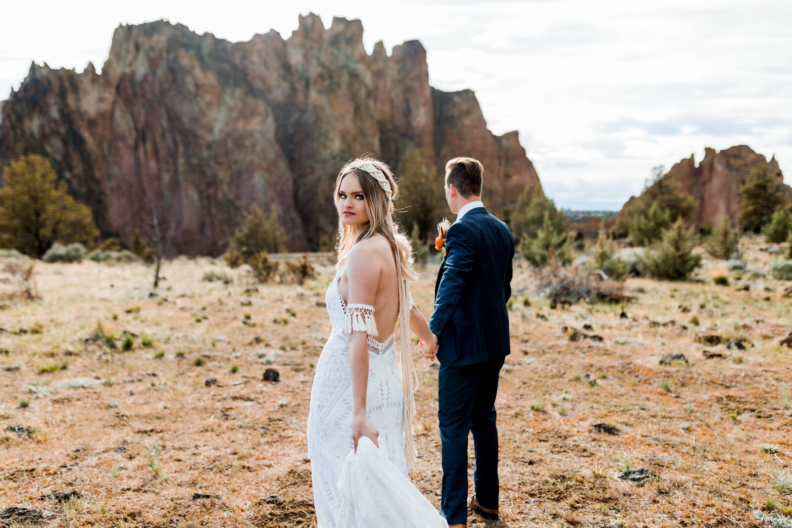 Couple standing together in a desert landscape with rocky cliffs, highlighting styled shoots for adventurous photographers in the Pacific Northwest.