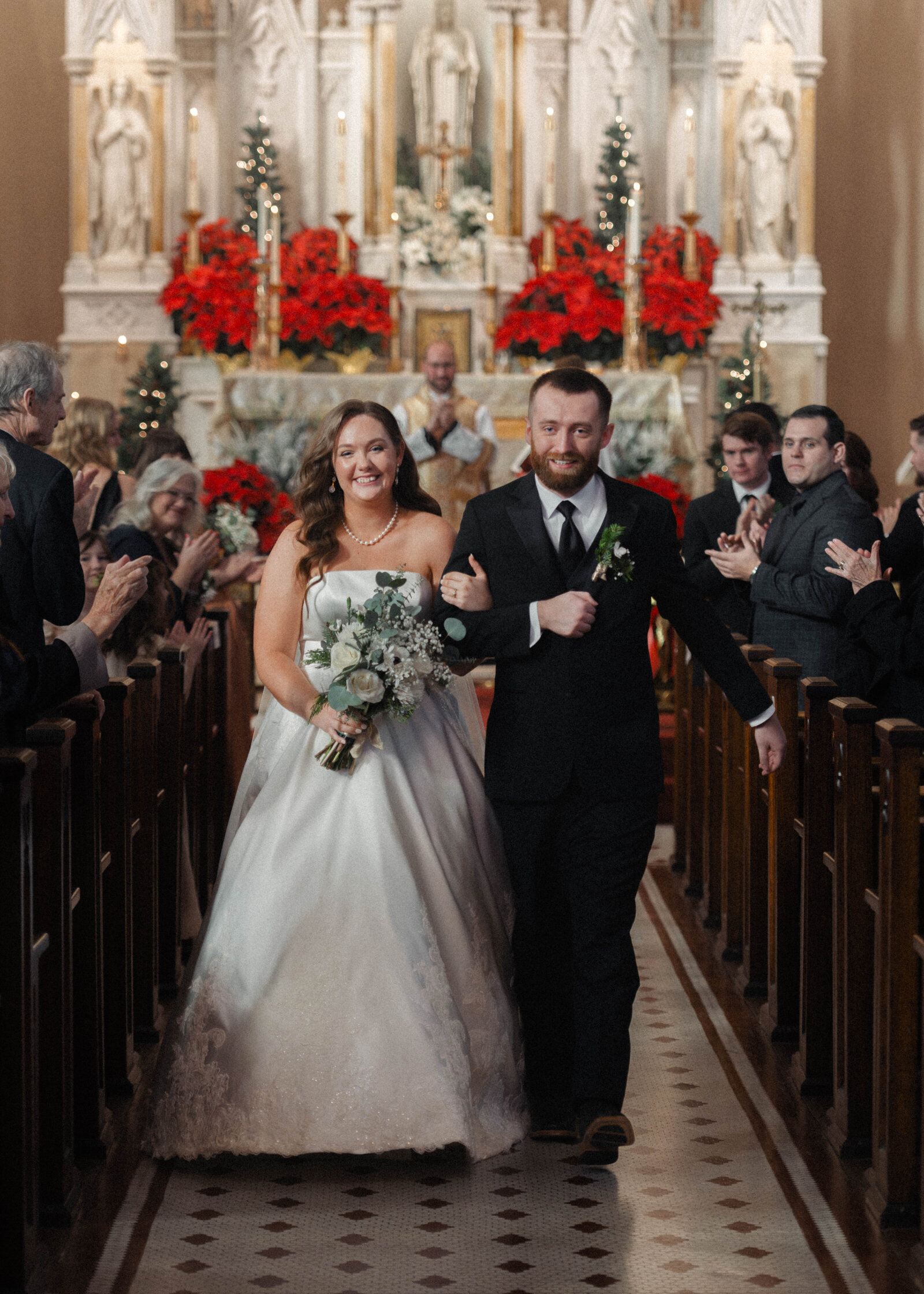 a catholic bride and groom joyfully and tearfully walk back down the aisle at the end of their catholic wedding mass at Emmanuel Catholic church in dayton ohio