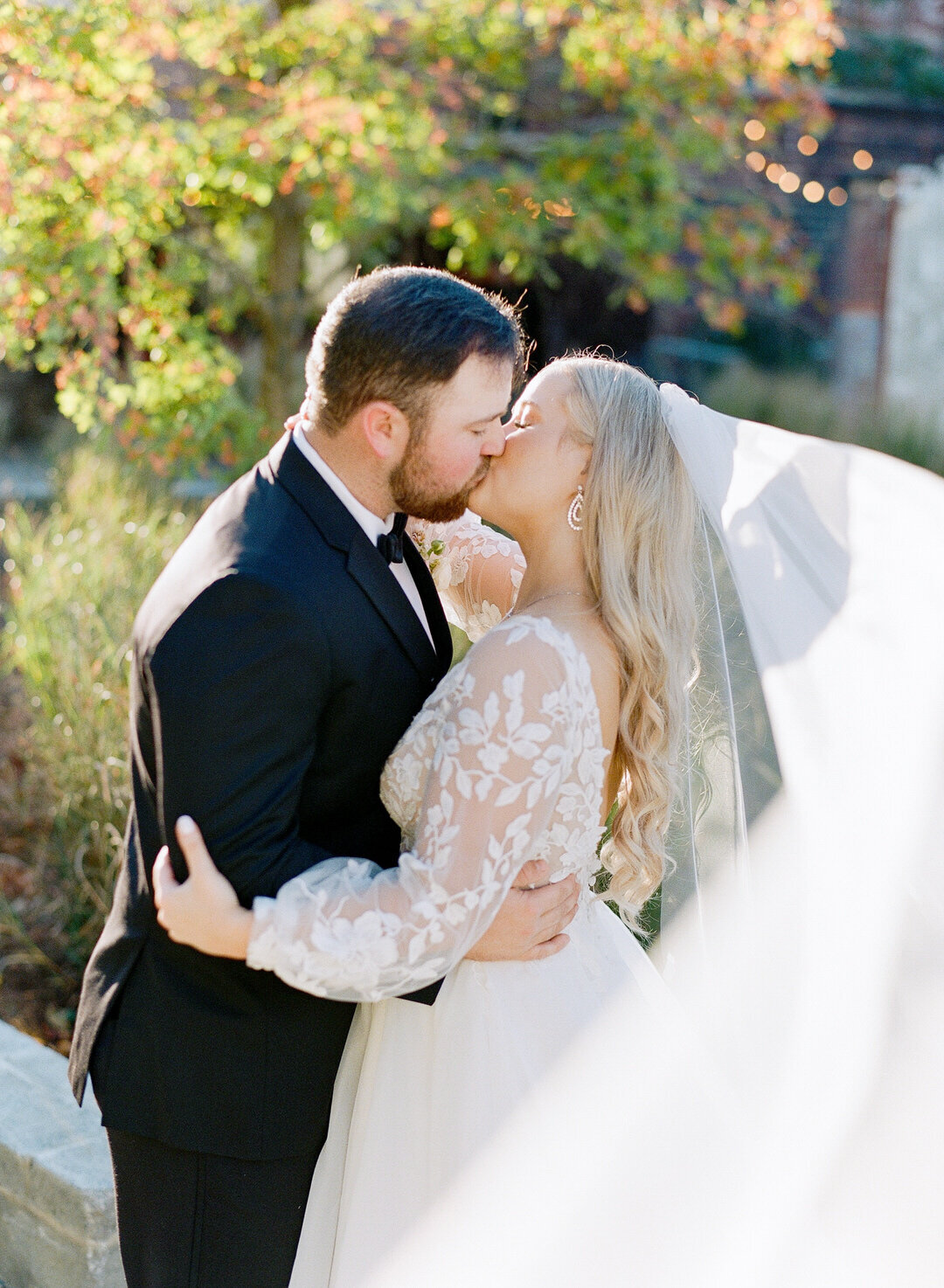 Bride and Groom Kissing with brides veil blowing in wind