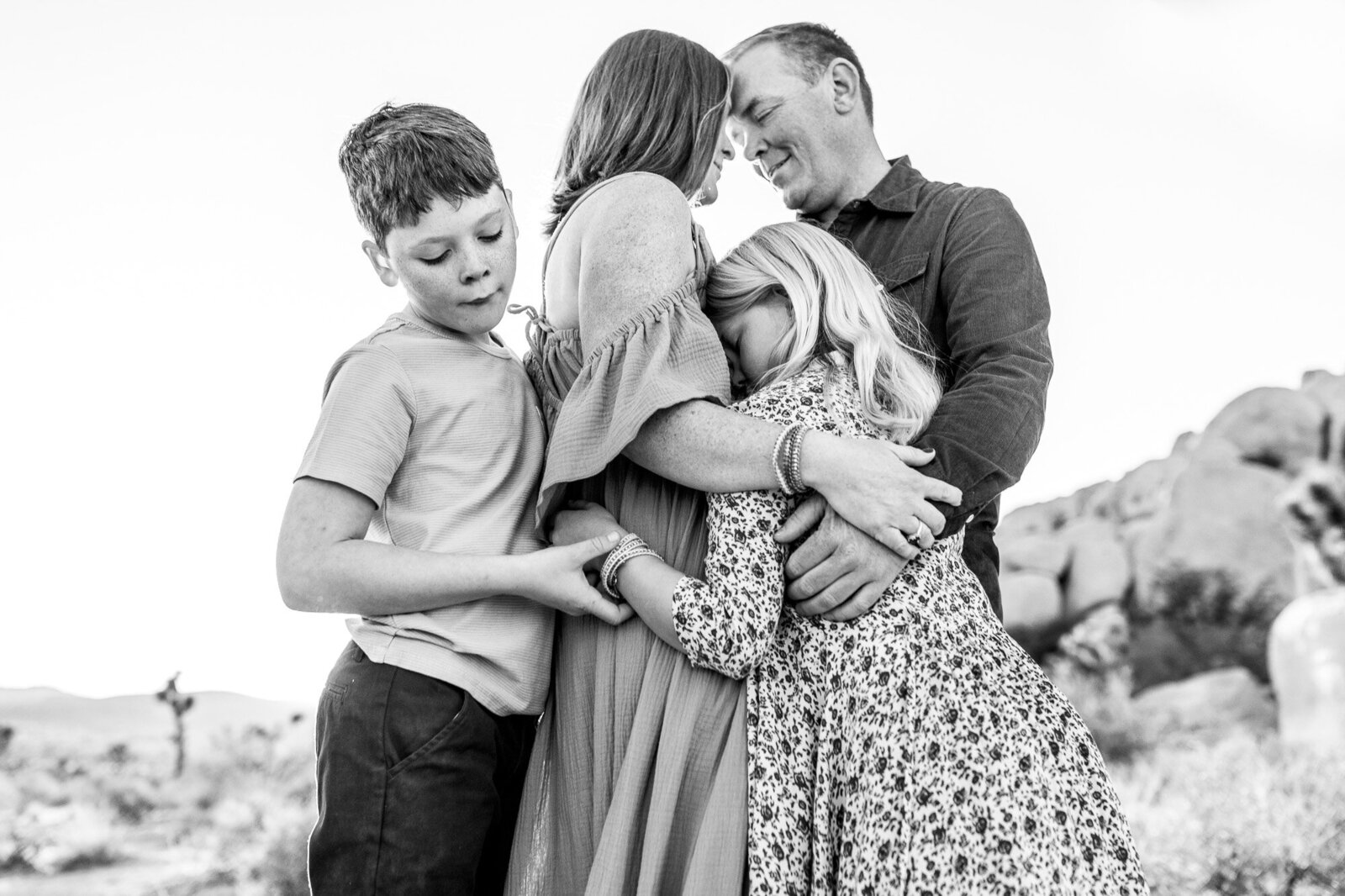 Black and white image of family hugging at a Joshua Tree photo spot.