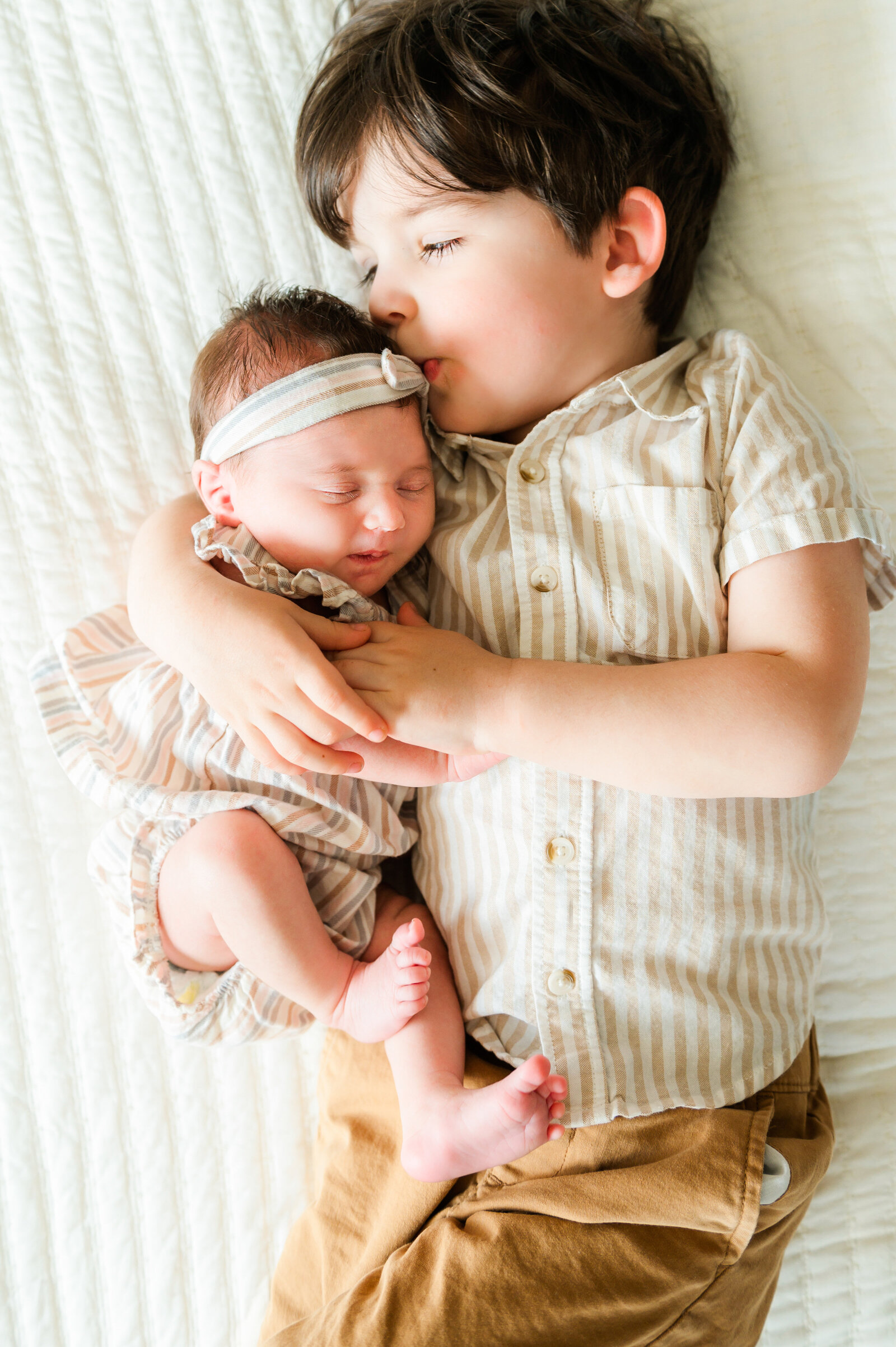big brother in bed holding is newborn sister during an in home newborn photography session