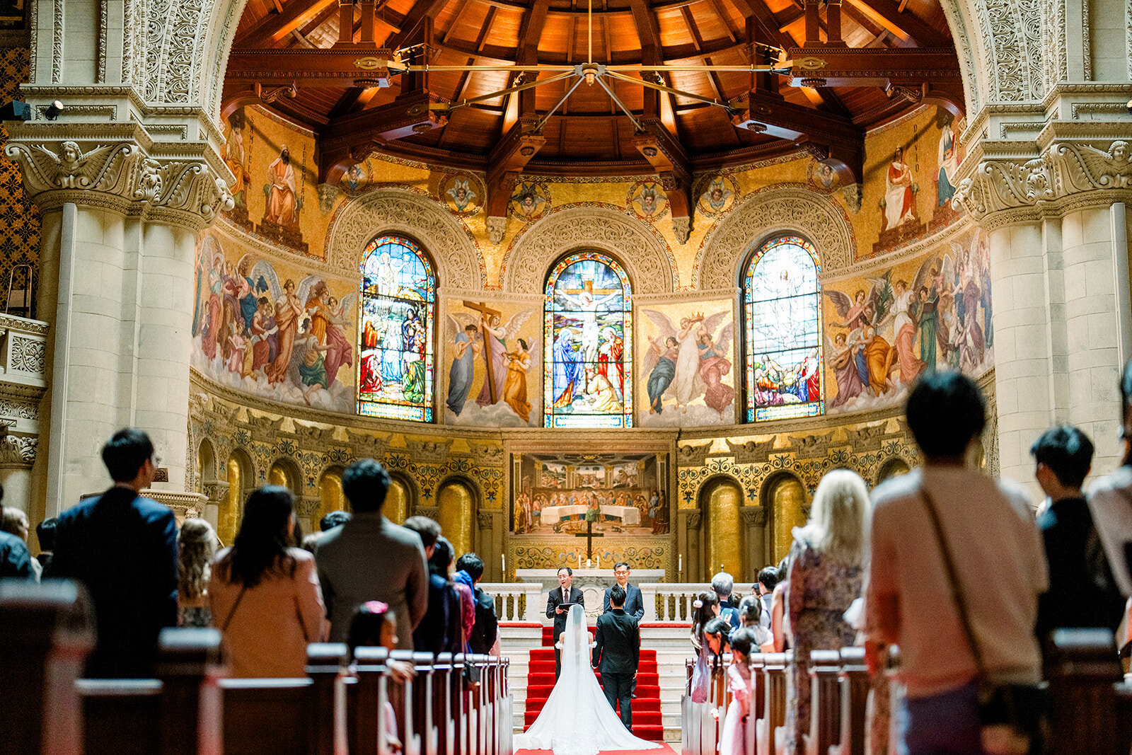 The bride and groom exchange vows in the magnificent setting of Stanford Memorial Church, surrounded by stunning architecture and stained glass windows.