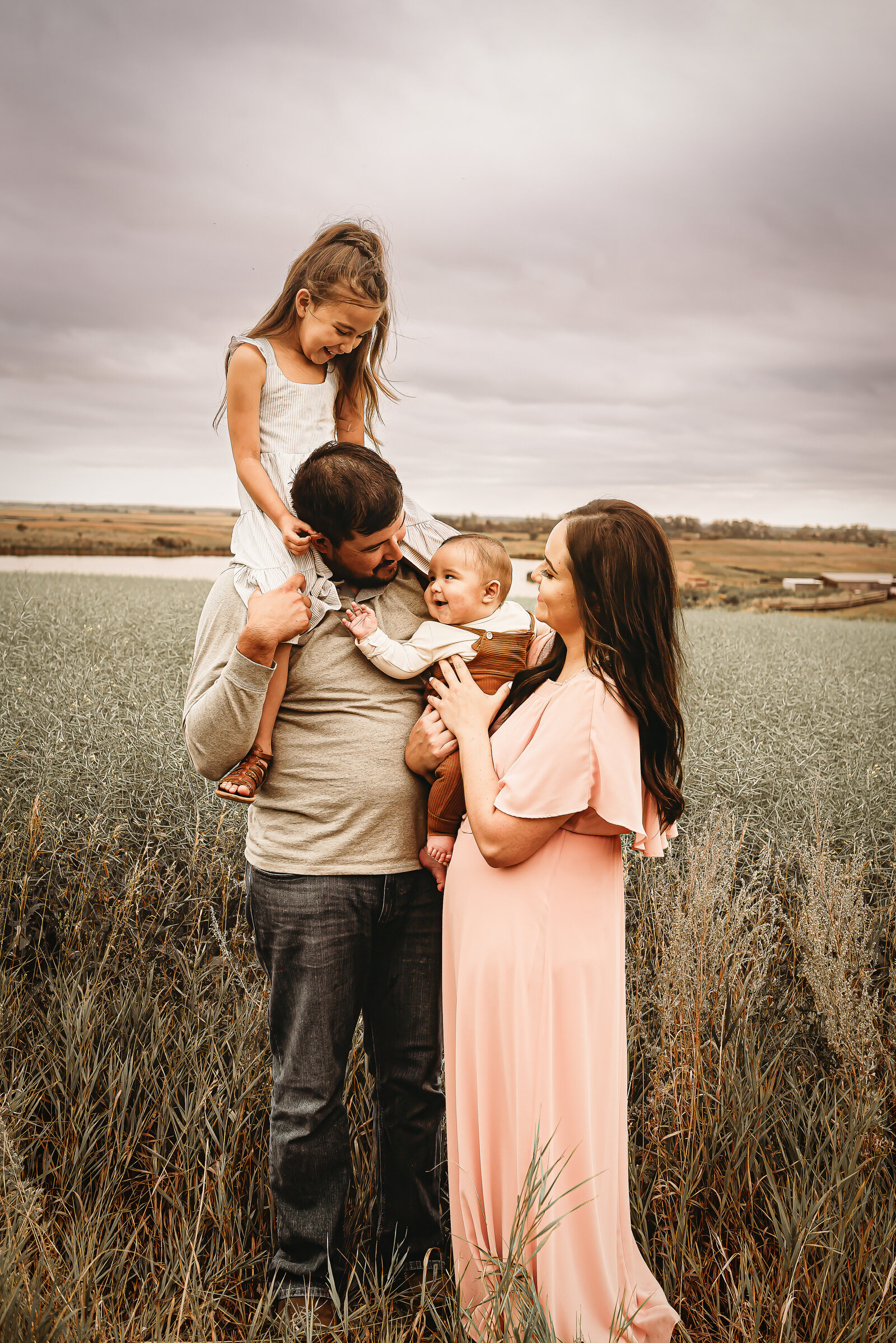 Deep in the prairie near Belcourt, ND, as family embraces while laughing together during their family session in their baby's first year membership.