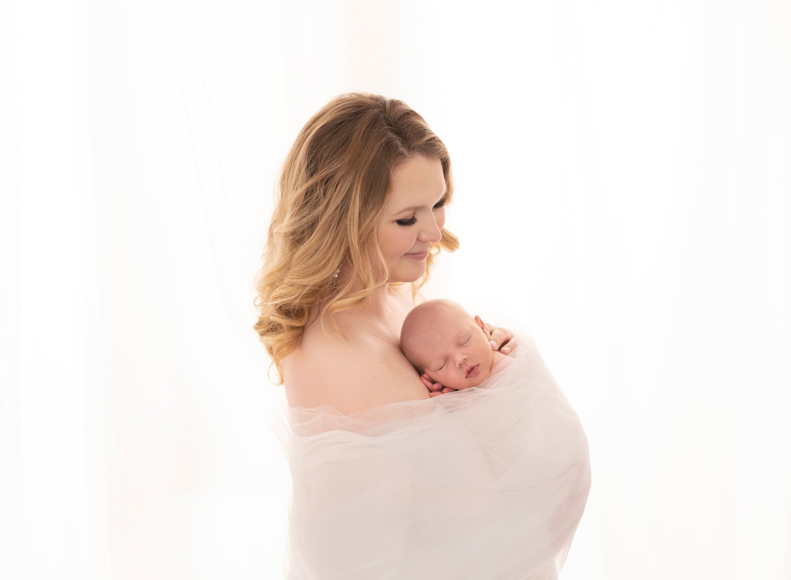 a mother holding her new baby and wrapped in tulle