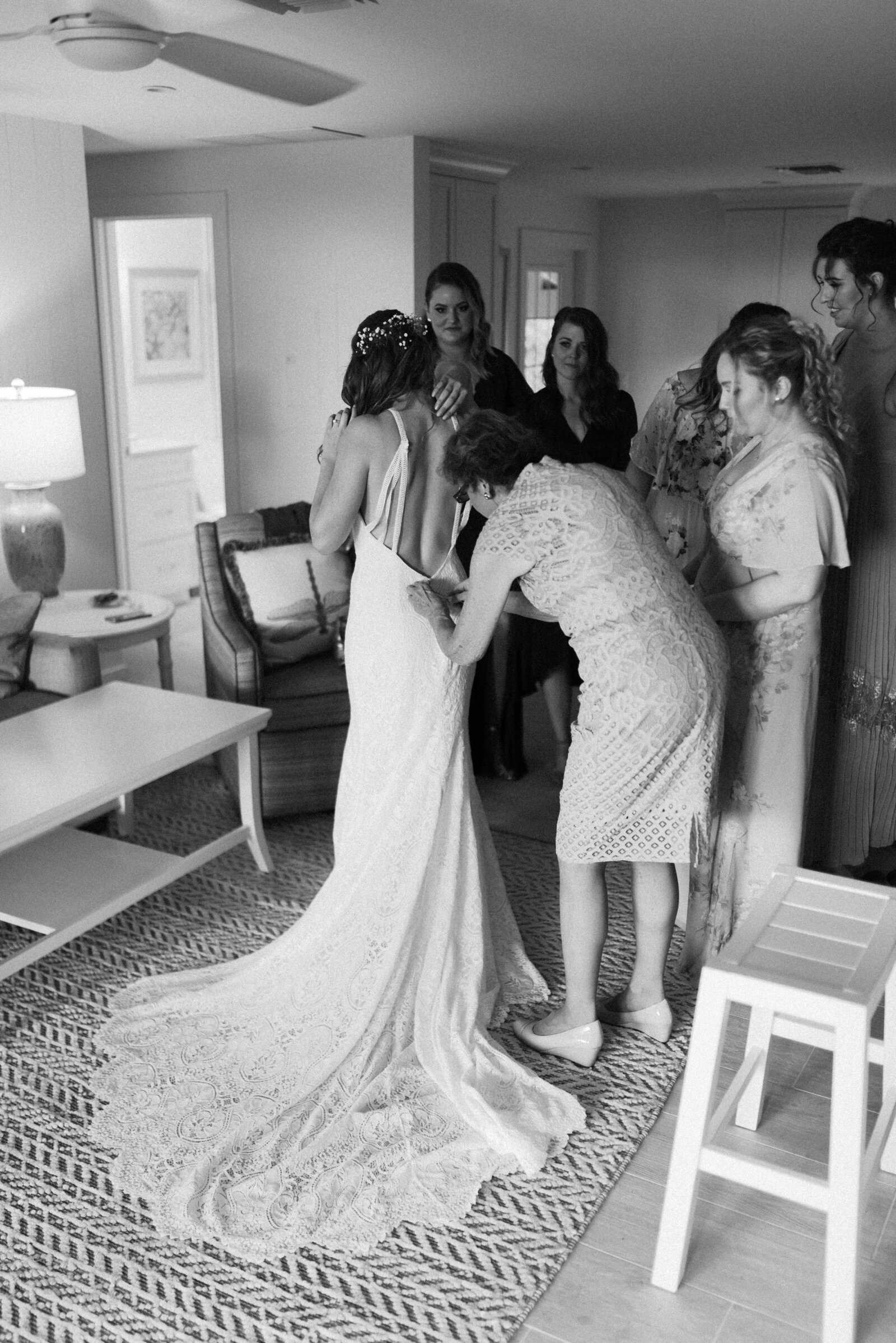 black and white photograph of mother of the bride helping to close the back of the brides wedding dress