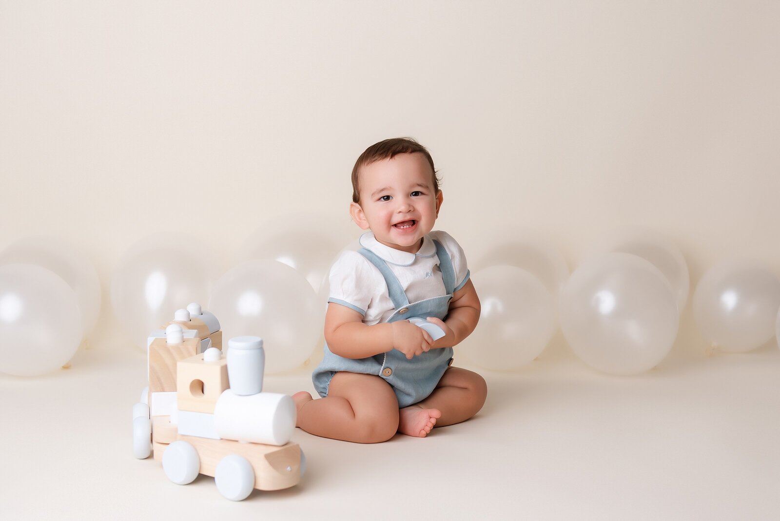 Cake smash photographer near me creates first birthday portraits with balloons and train.