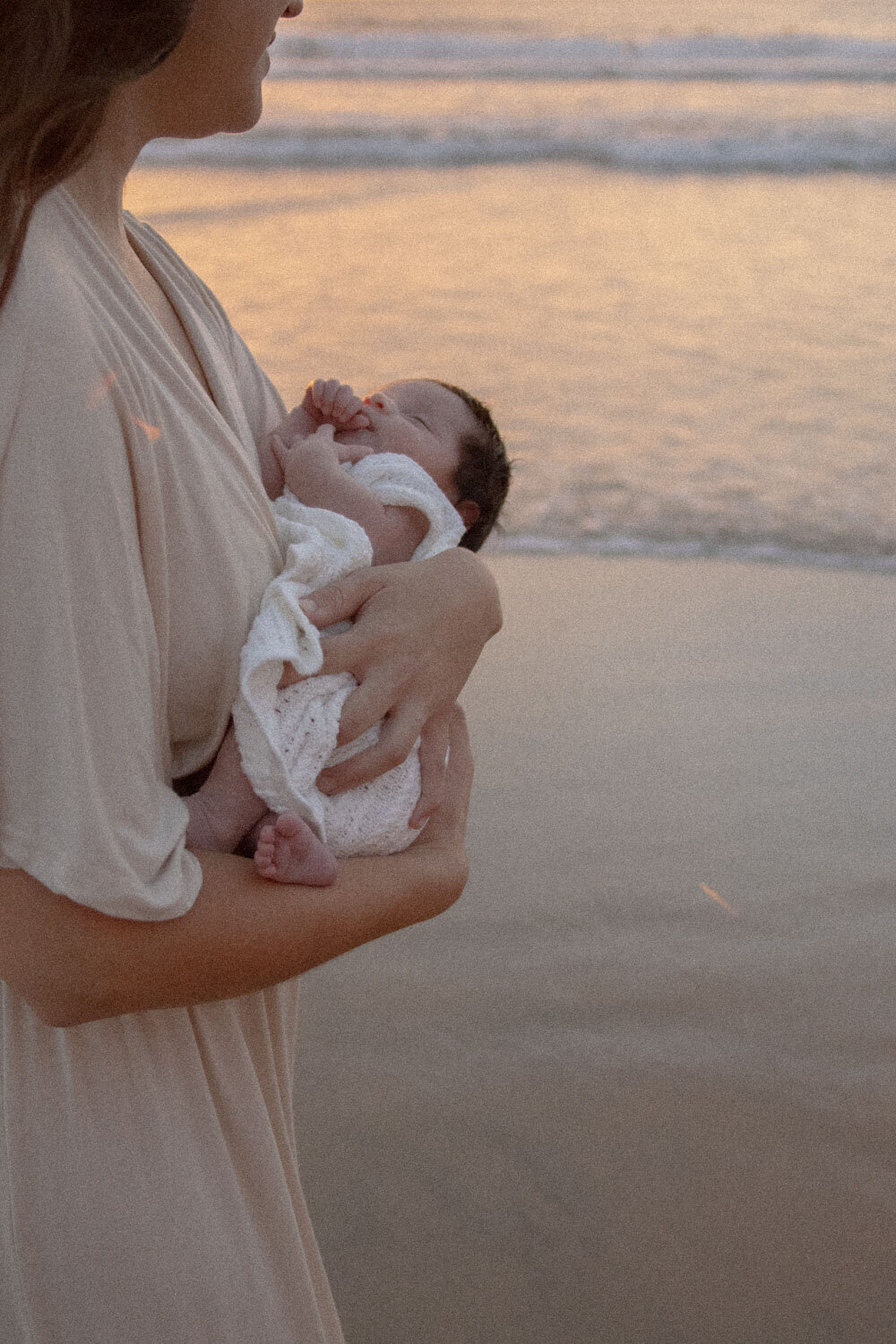 Mother holding her newborn by the water