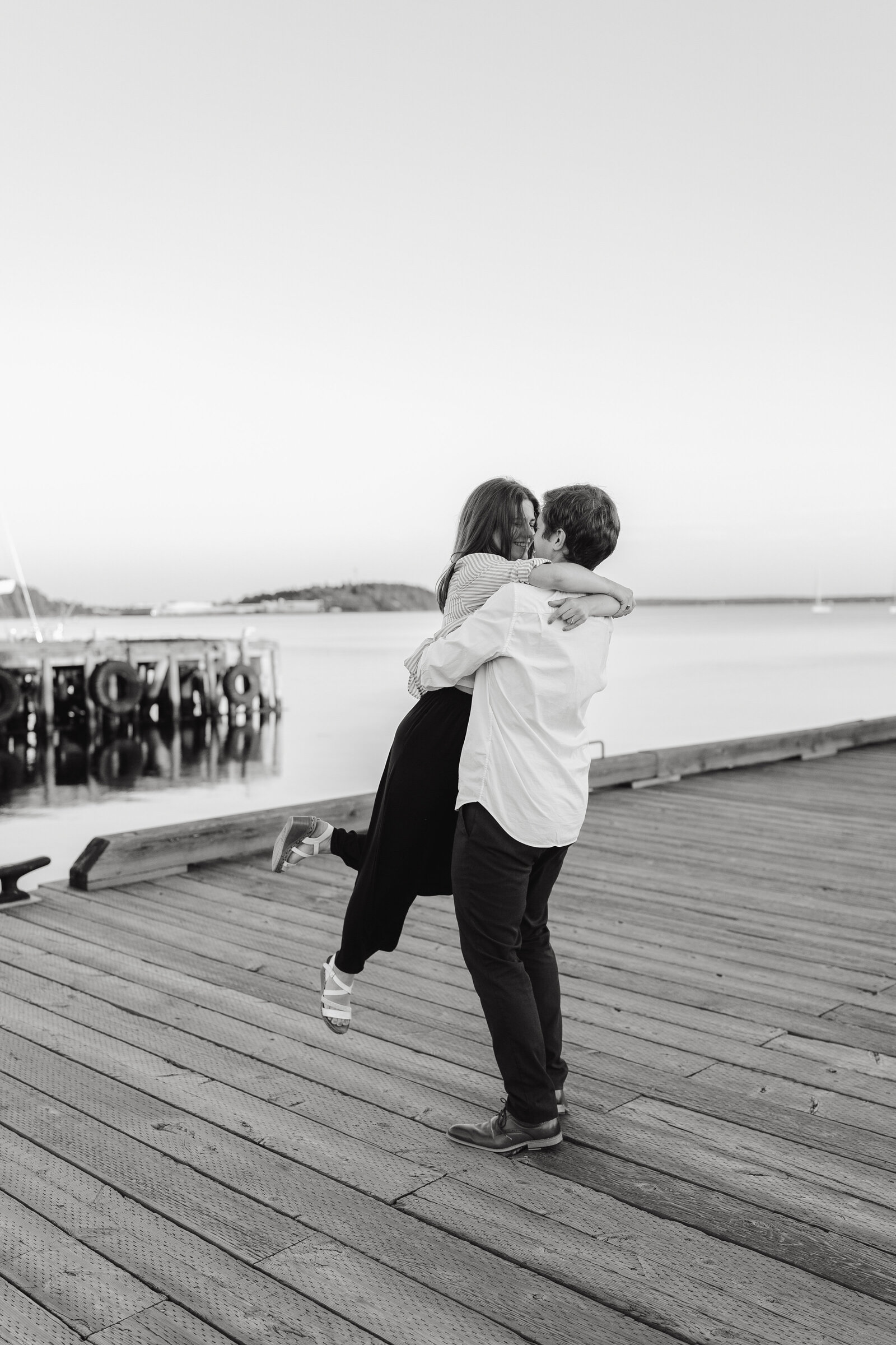 A man picks up his fiance and spins her around on the dock in Lunenburg. 