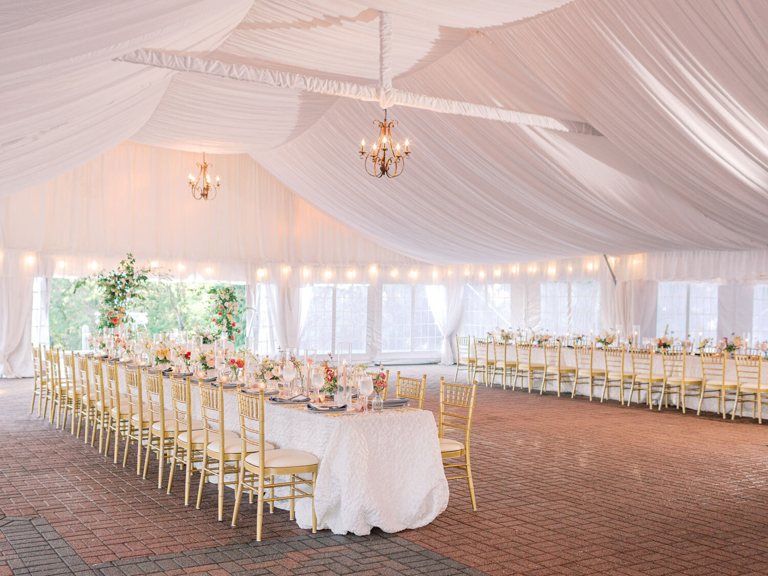 Elegant wedding reception tent with draped ceiling and gold chairs