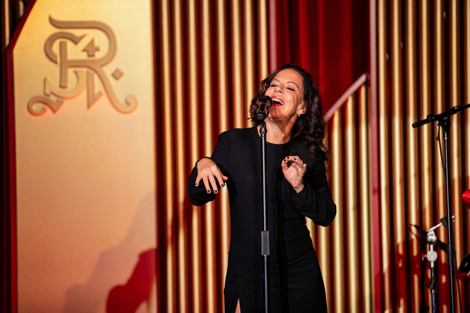 Woman singing passionately on stage in a black dress