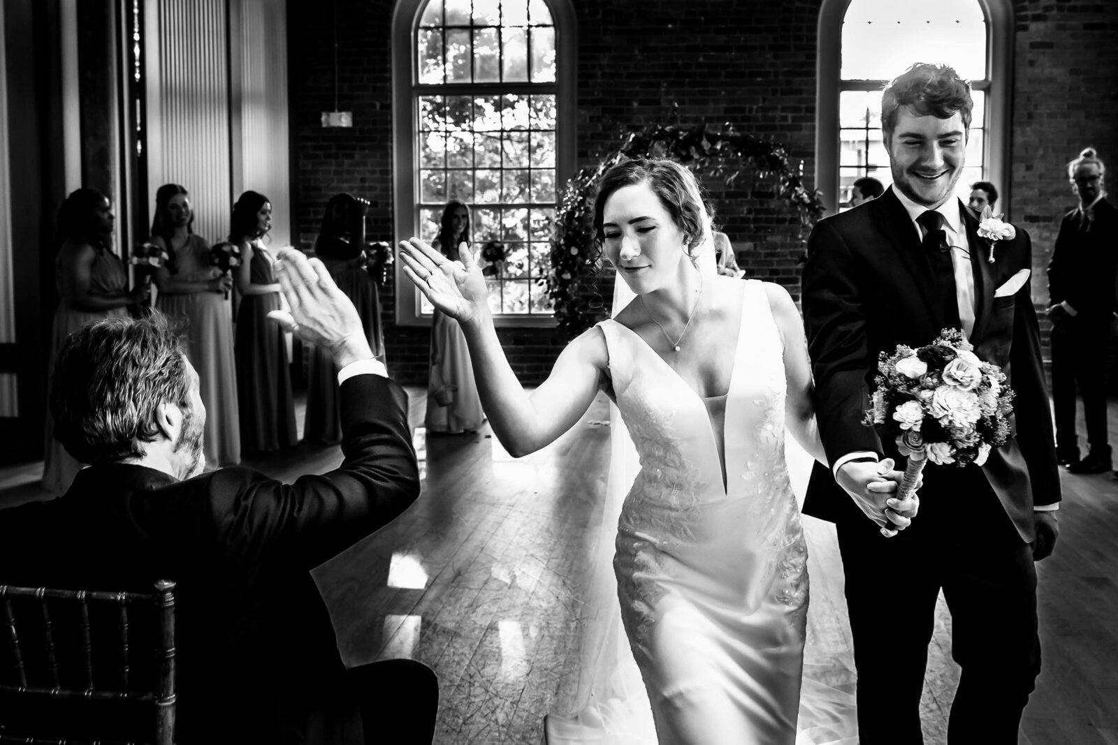bride high-fives her dad as she and the groom recess down the aisle after their wedding ceremony