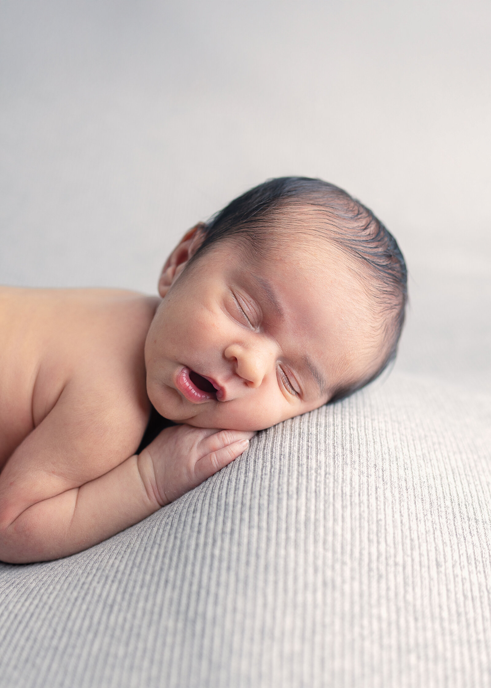 Newborn baby peacefully sleeping on soft neutral blanket during studio session in Bergen County, NJ