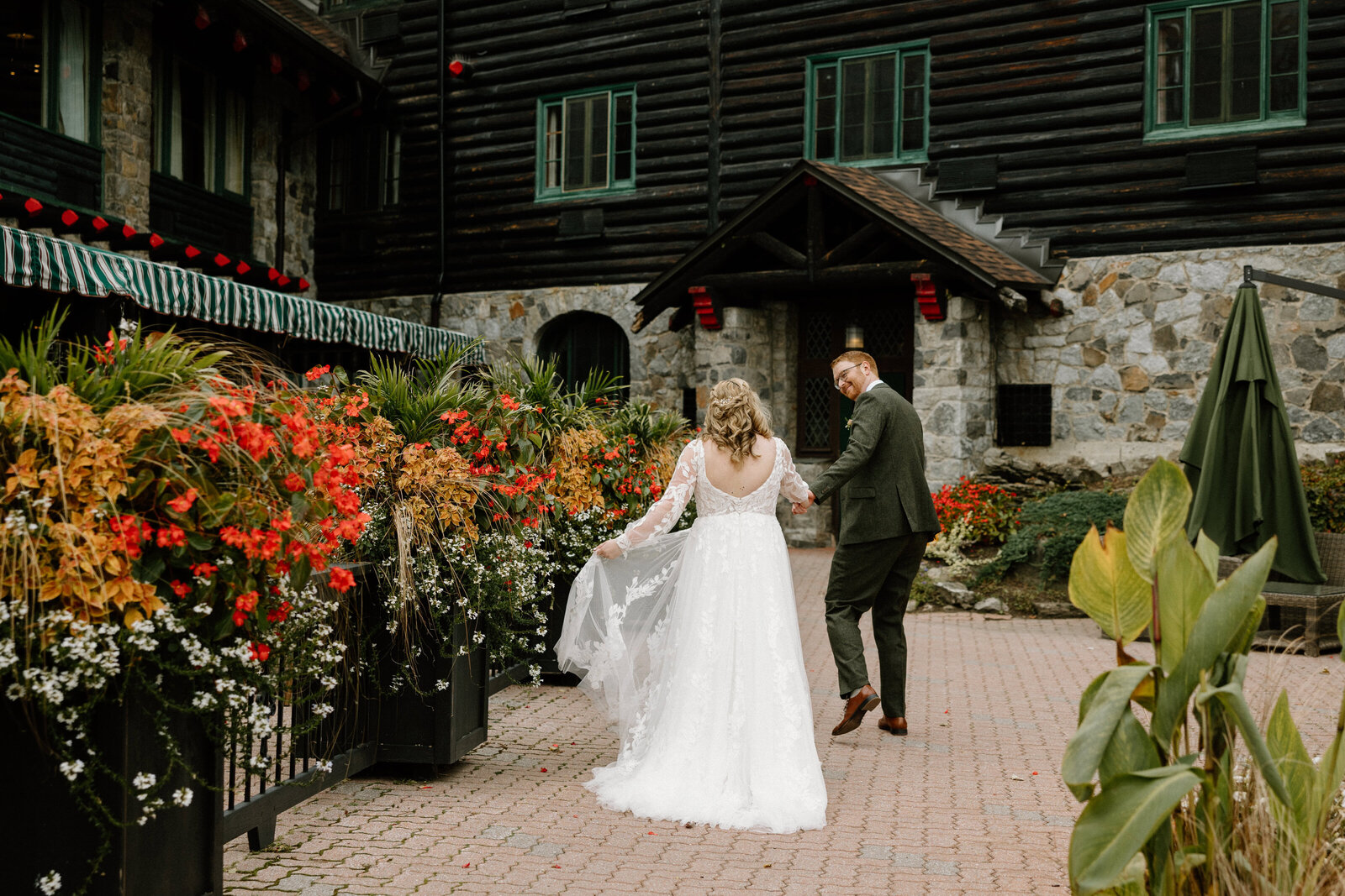 The bride and groom walking hand in hand as they walk towards the entrance of the wedding venue
