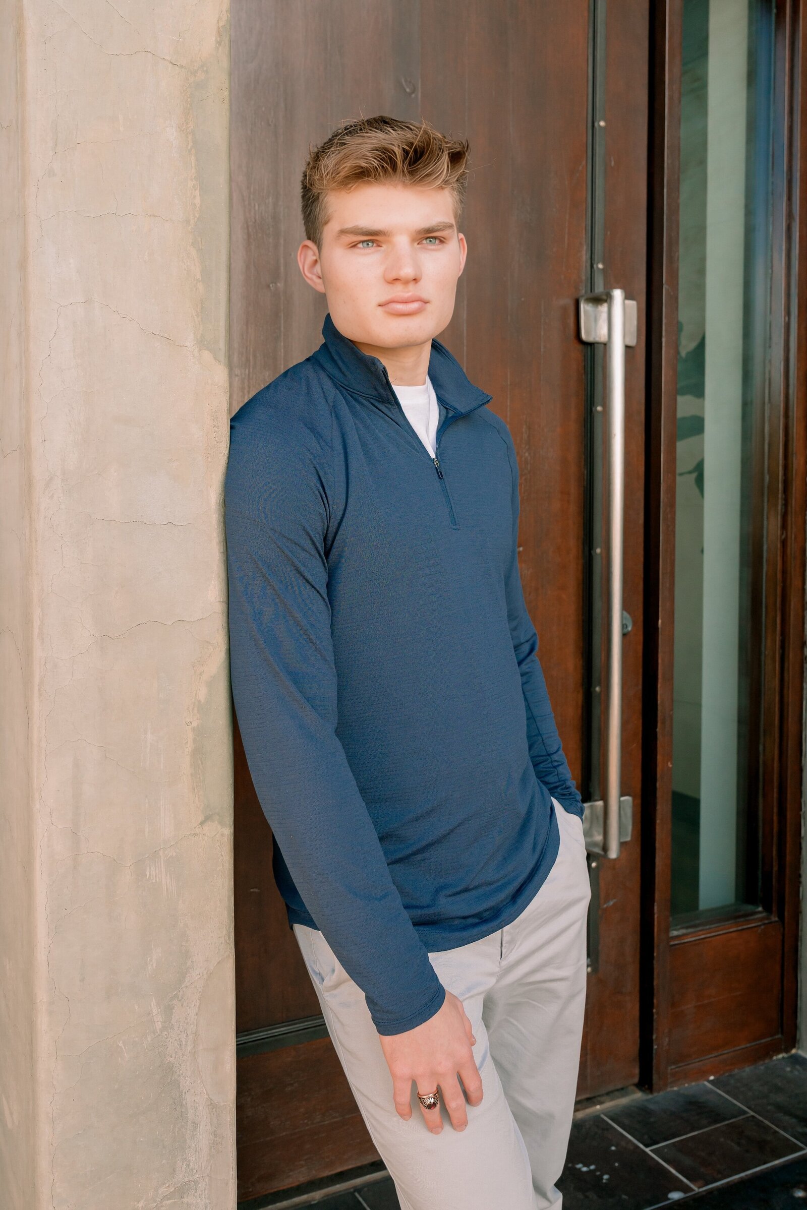 senior boy boy in blue shirt leaning against wall at DC Ranch market street 
