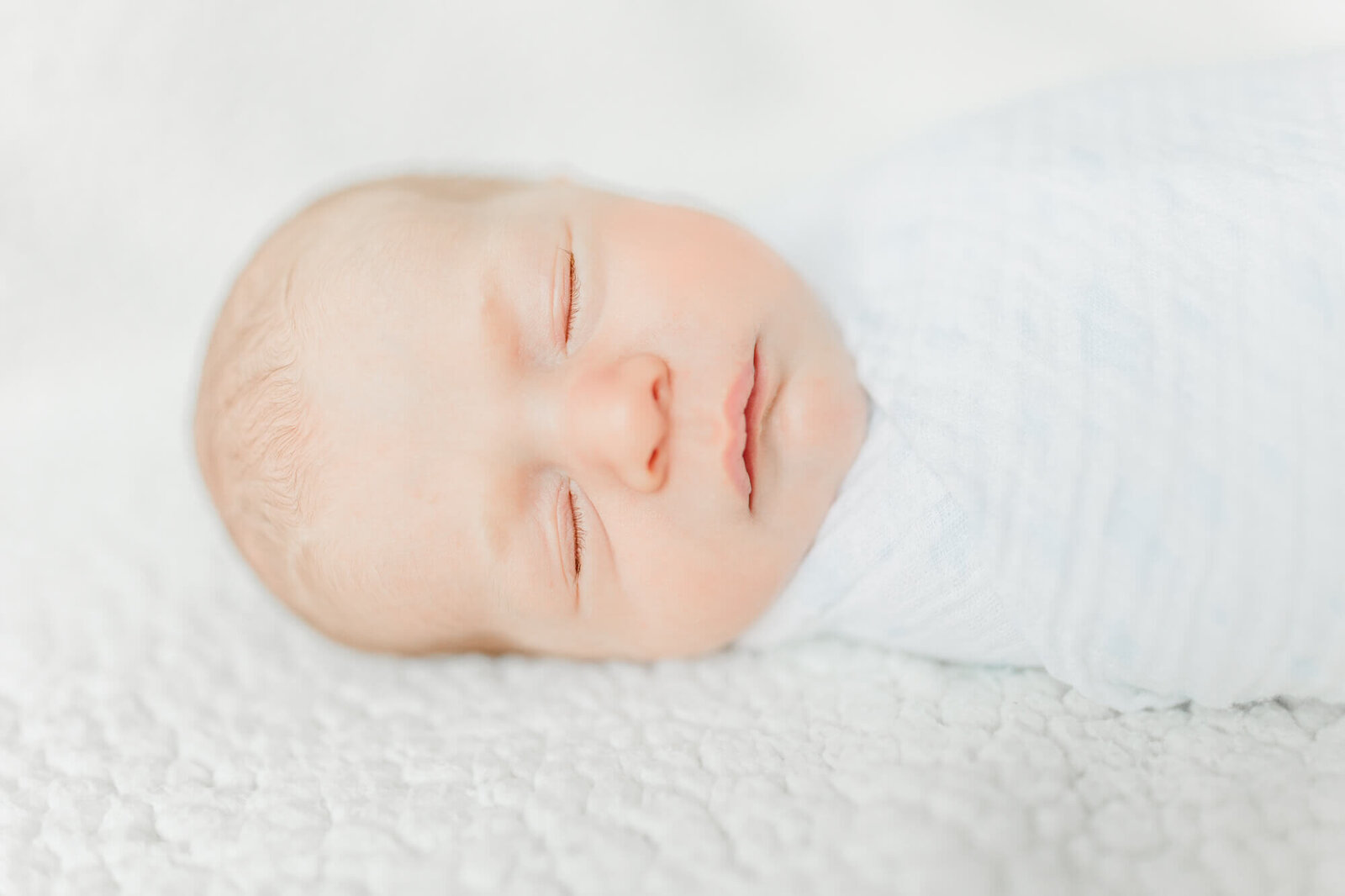 Face of a sleeping, swaddled newborn