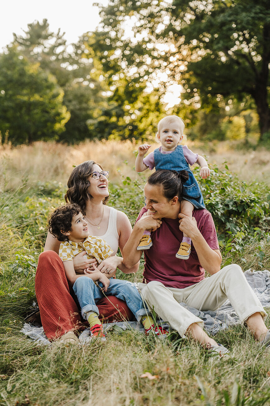 two moms laugh in field with kids during sunset boston photos