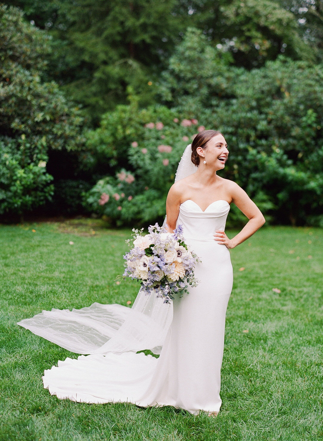 bride laughing holding bouquet and hand on her hip