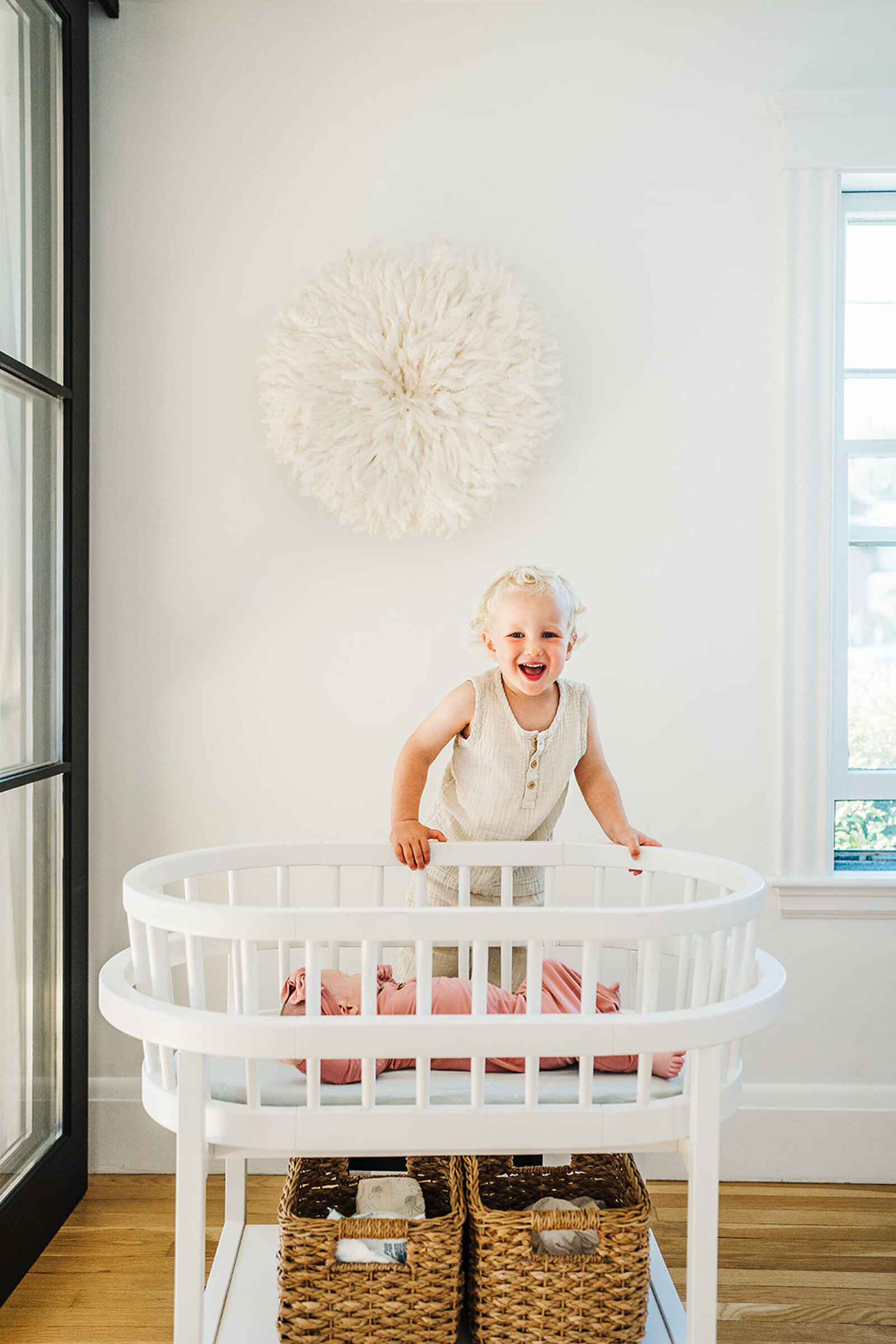 toddler boy smiles over top of bassinet