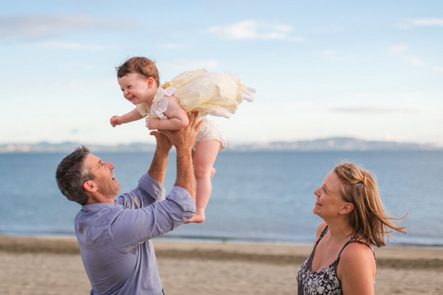 family tossing little girl in air