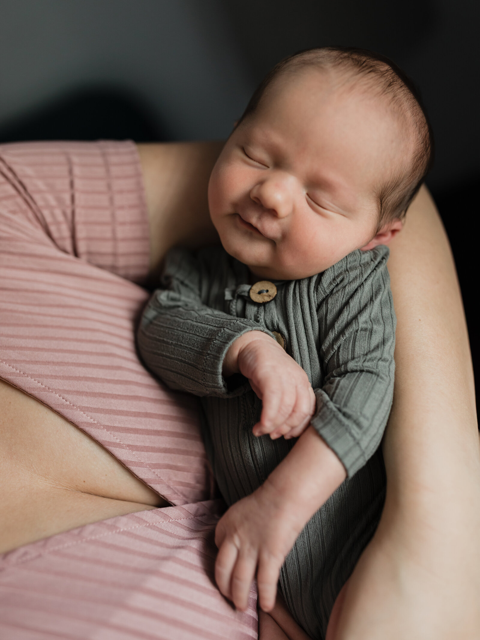mom cradling newborn baby boy in bedroom for in home lifestyle session 
