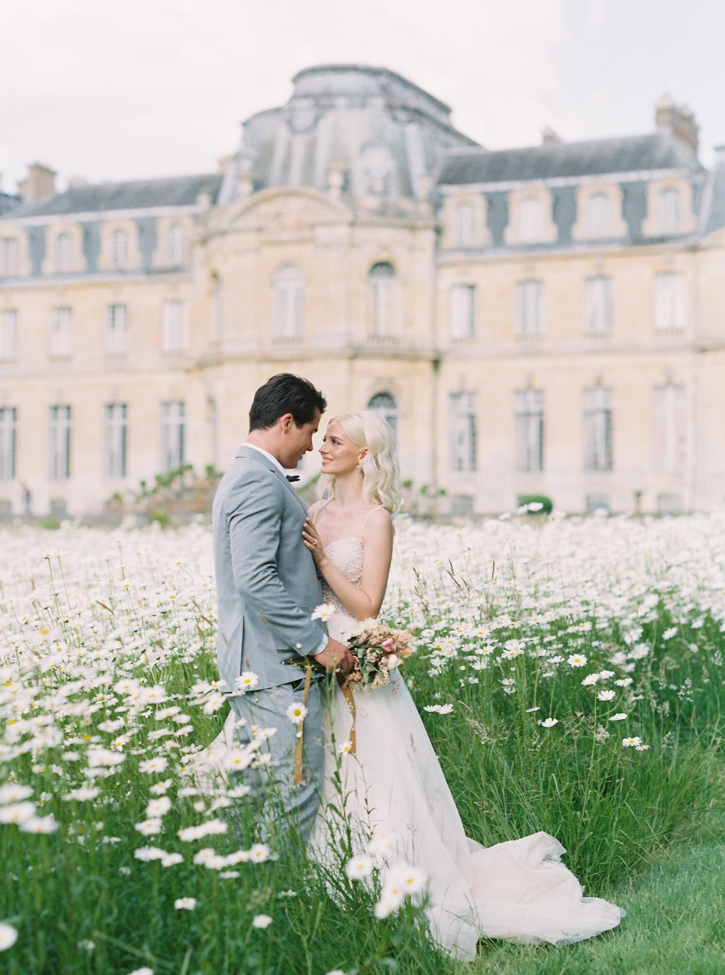 Bride and groom in a margarita flower field at Château de Champlâtreux