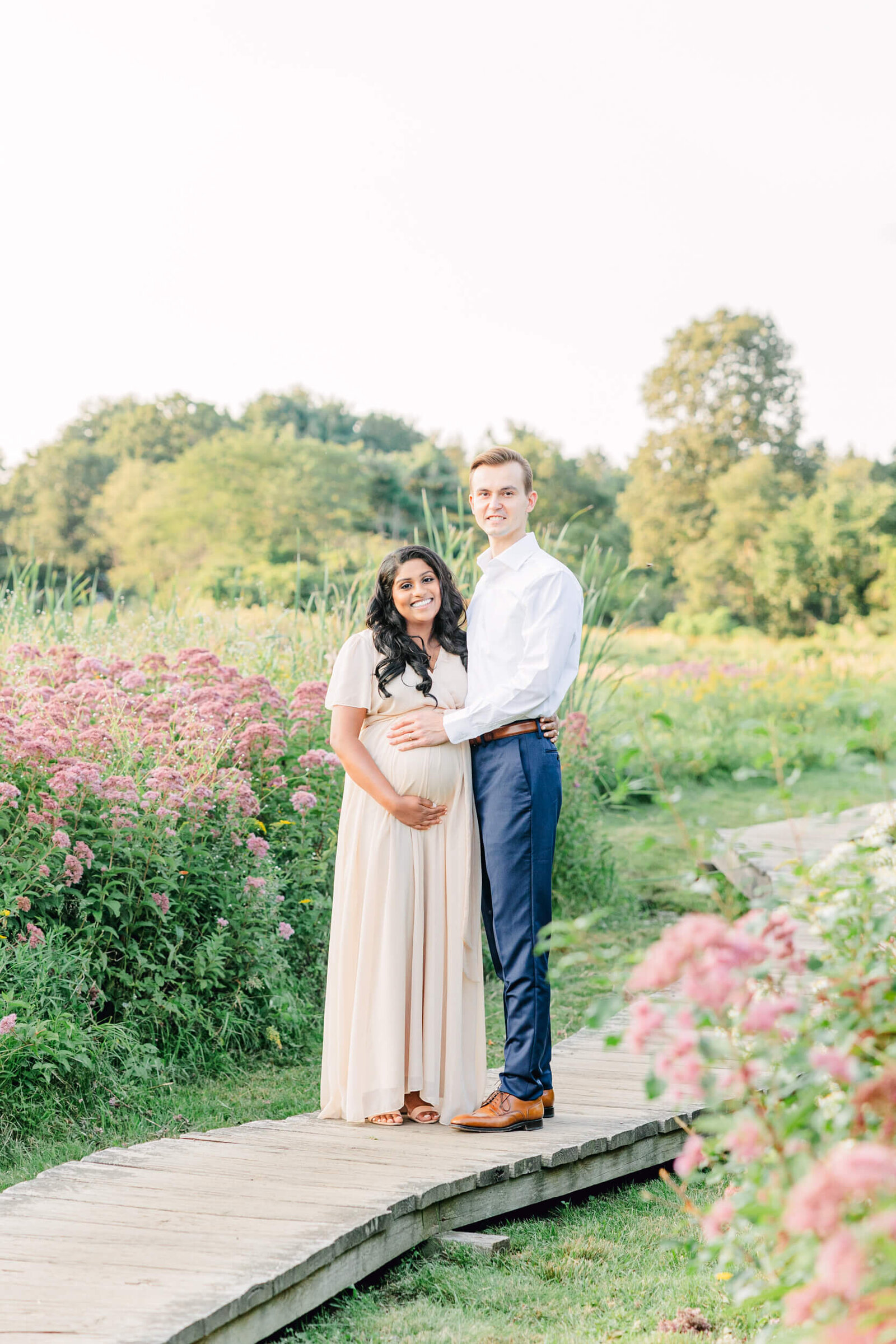 Pregnant woman and her husband stand together and smile