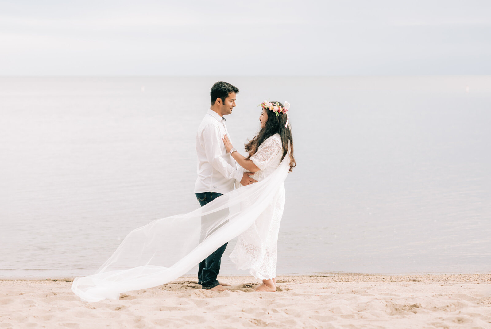 husband and pregnant wife standing on beach for maternity photos Cleveland maternity photographer