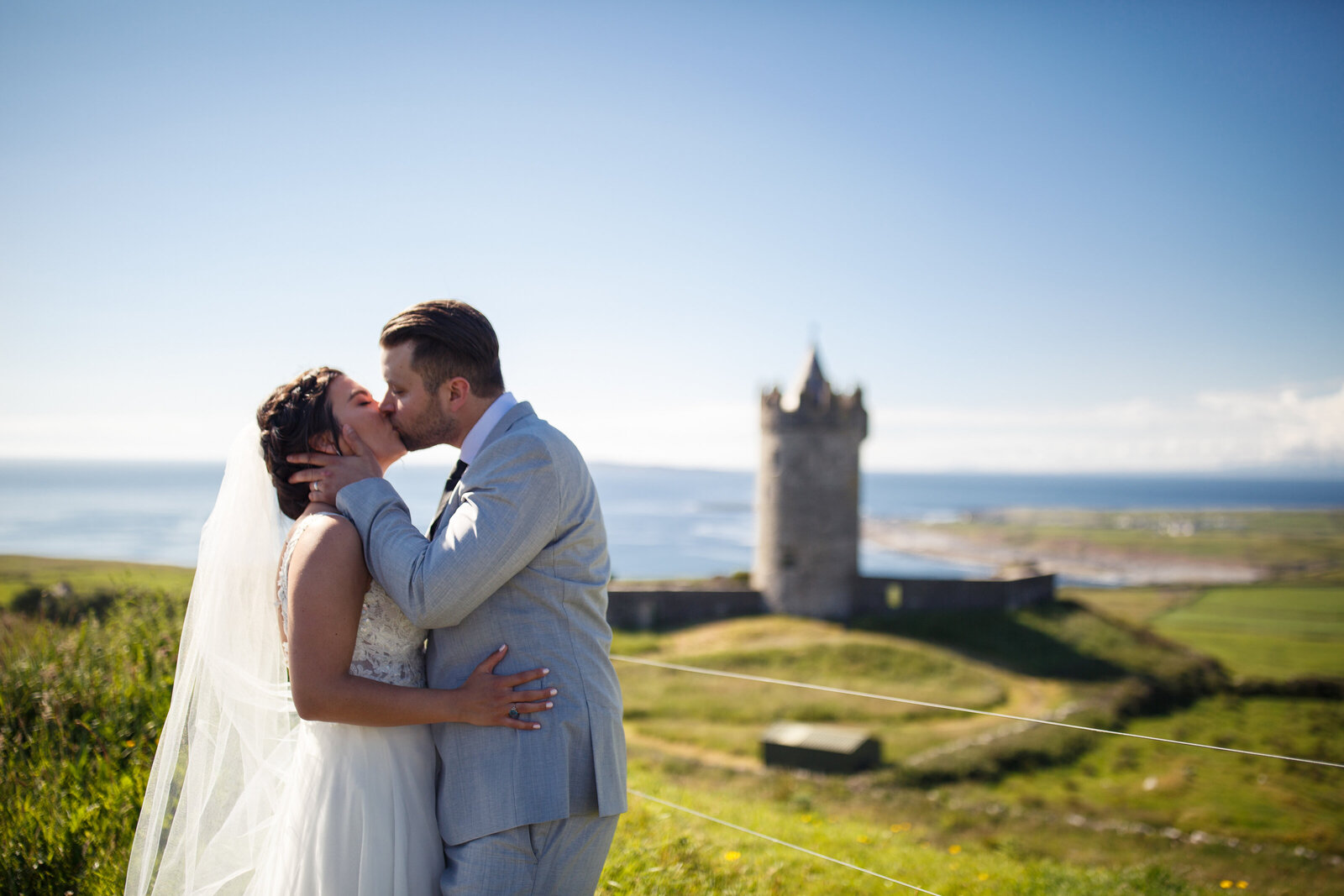 bride and groom kissing in front of a castle in ireland
