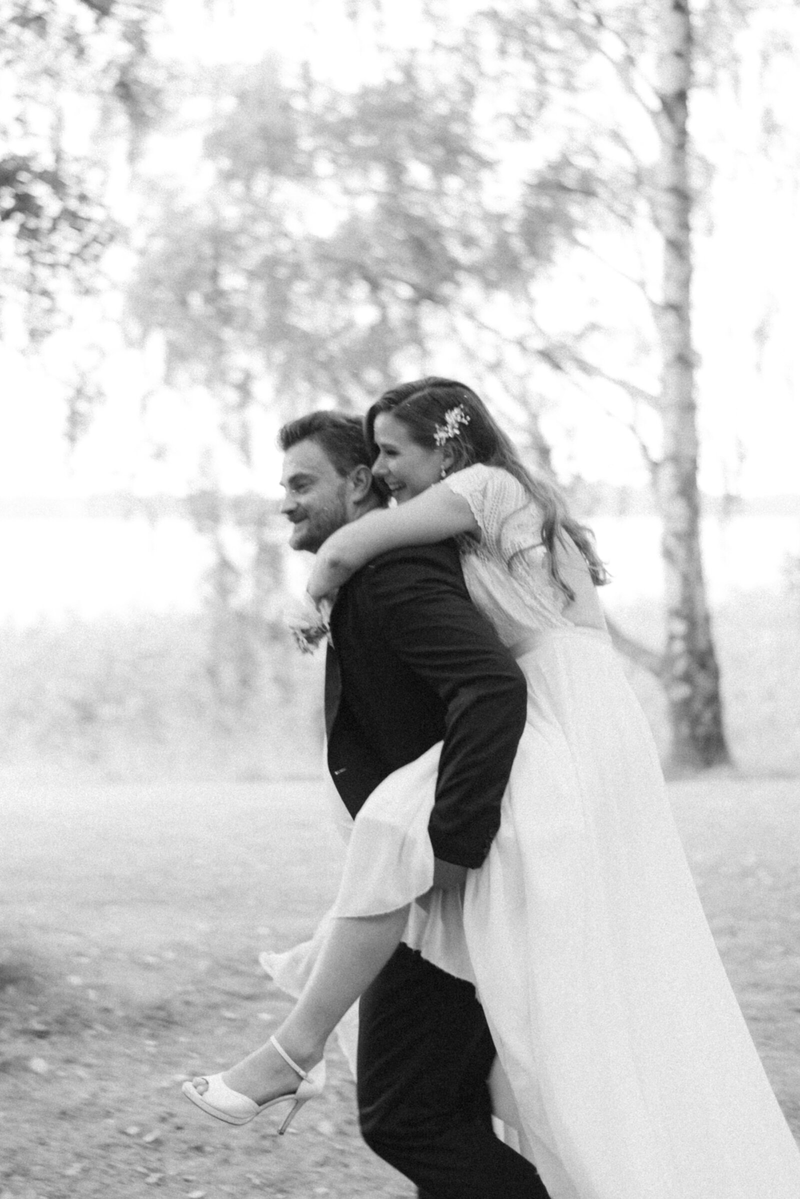 The gtoom is carrying the bride on piggyback in a wedding photograph by wedding photographer Hannika Gabrielsson.