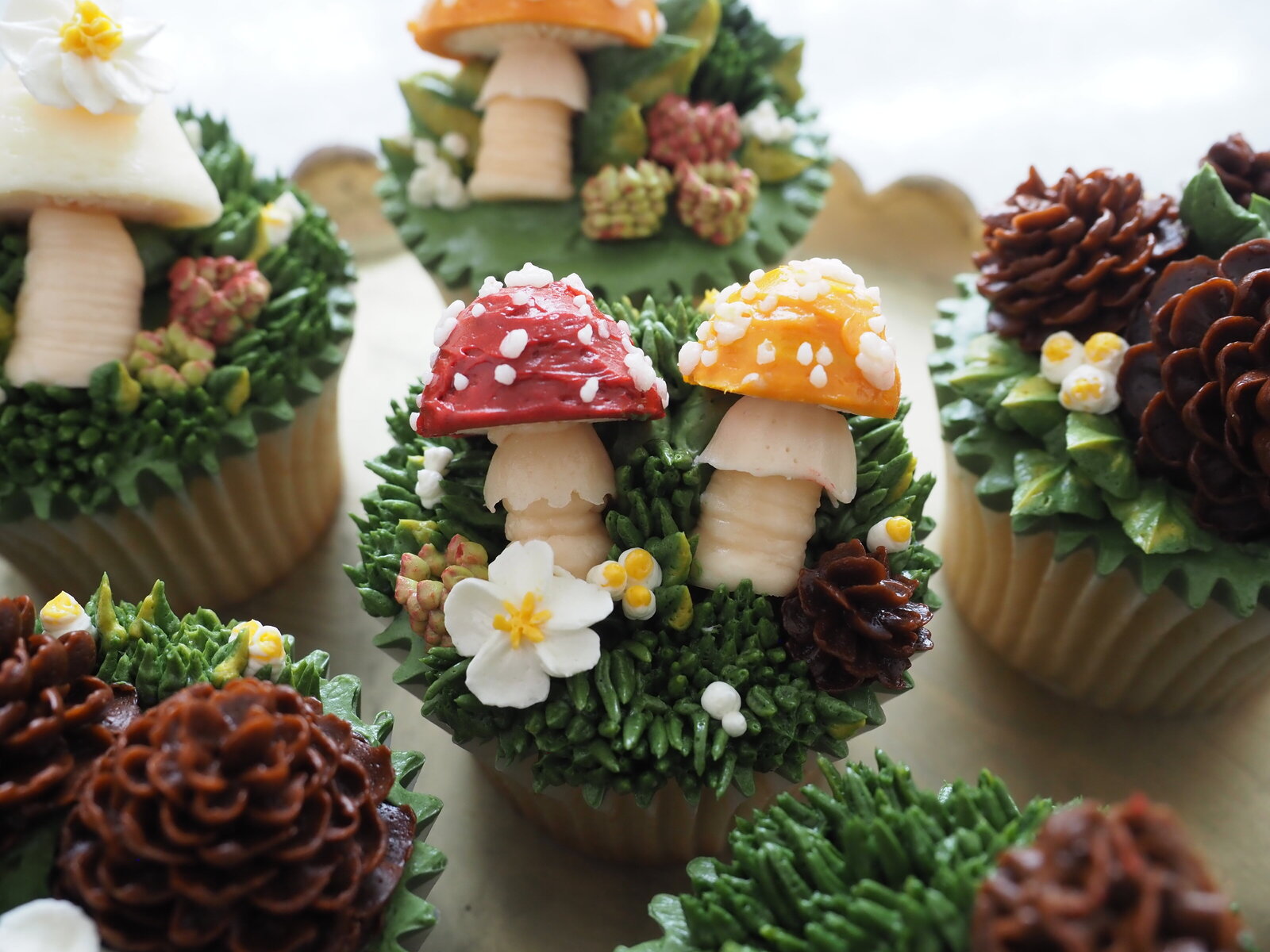 Close up of two mushrooms and flowers on a cupcake all made out of buttercream