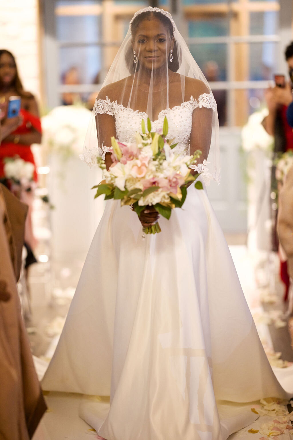bride walking down the aisle holding a bouquet of lilies