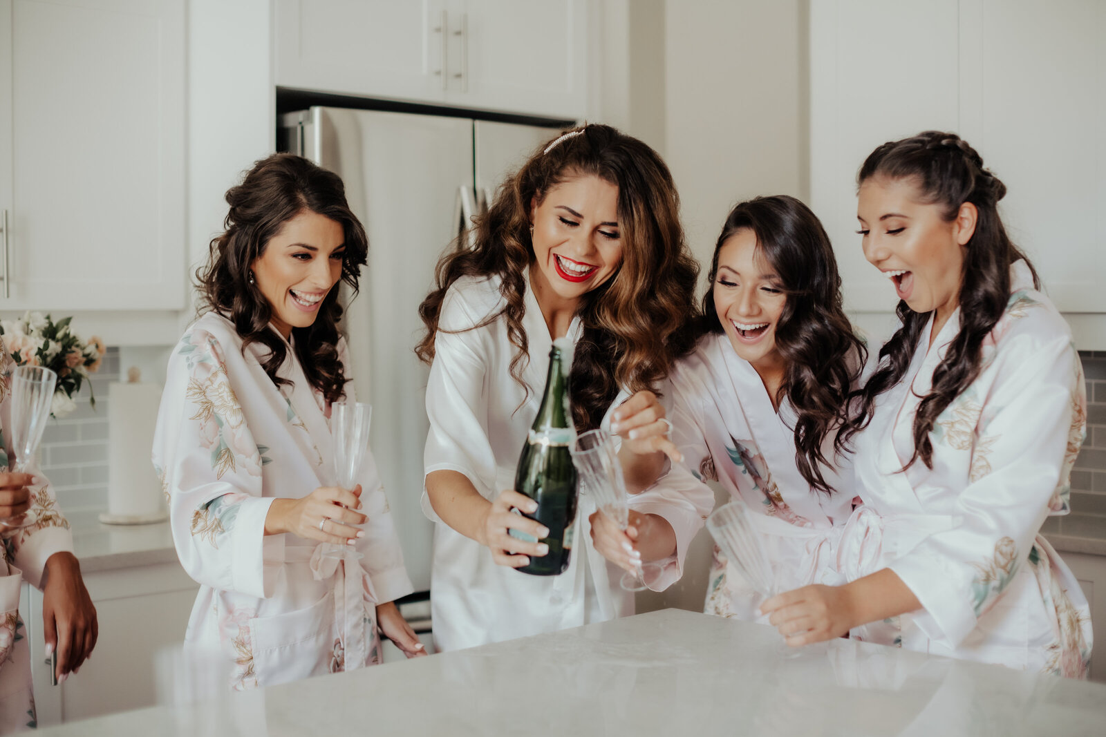 Bride popping champagne with bridesmaid